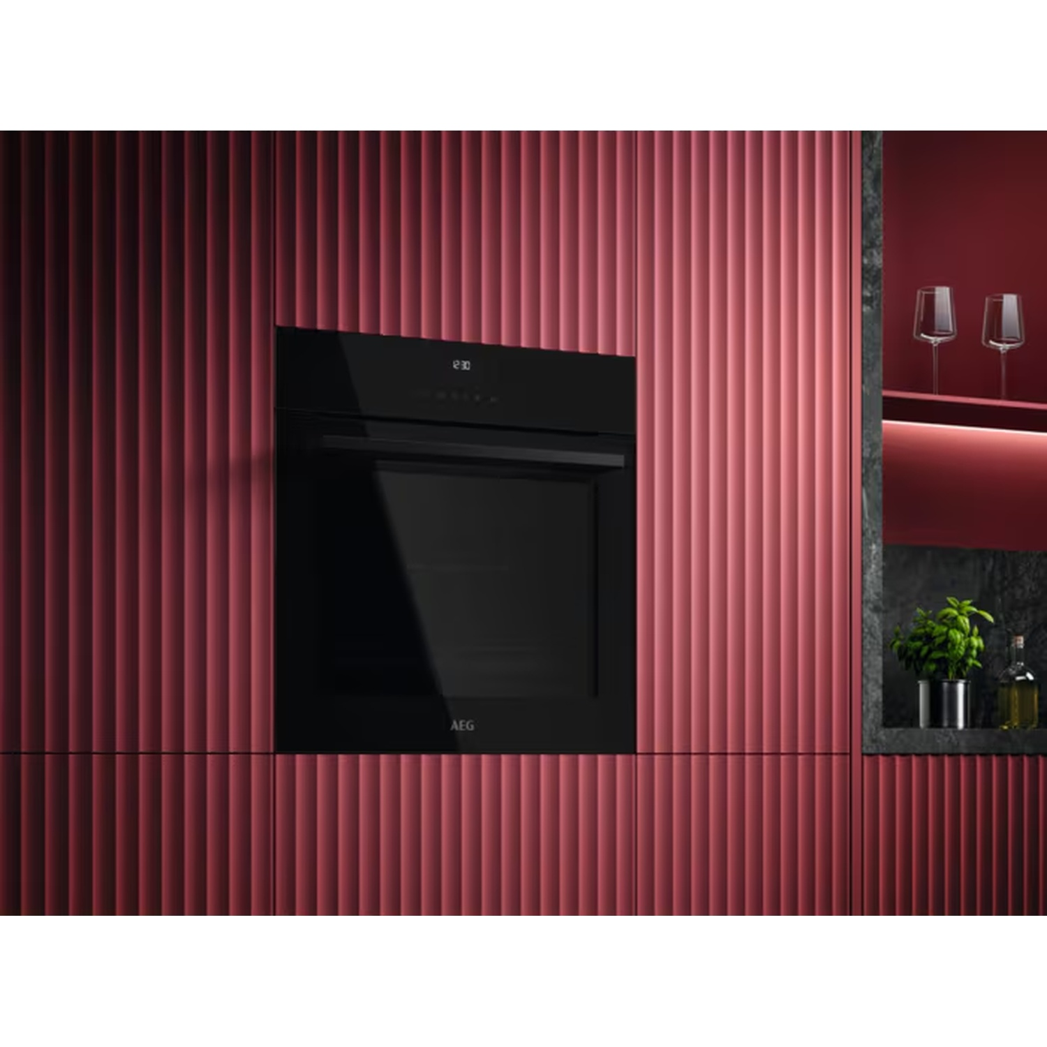 Un four encastrable noir moderne sur un mur rouge côtelé. Des verres sur une étagère à proximité.