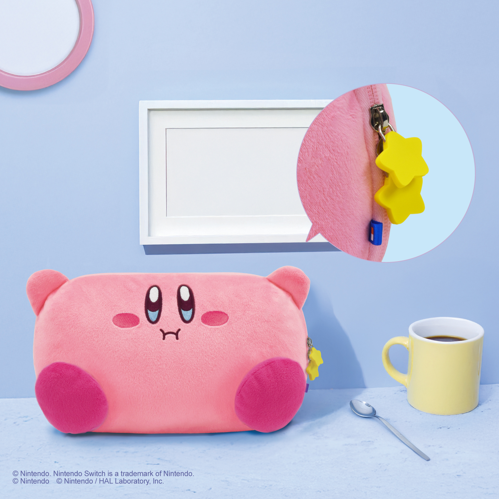 Eine rosa Kirbys-Plüschfigur mit Stern-Anhängern neben einer gelben Kaffeetasse.
