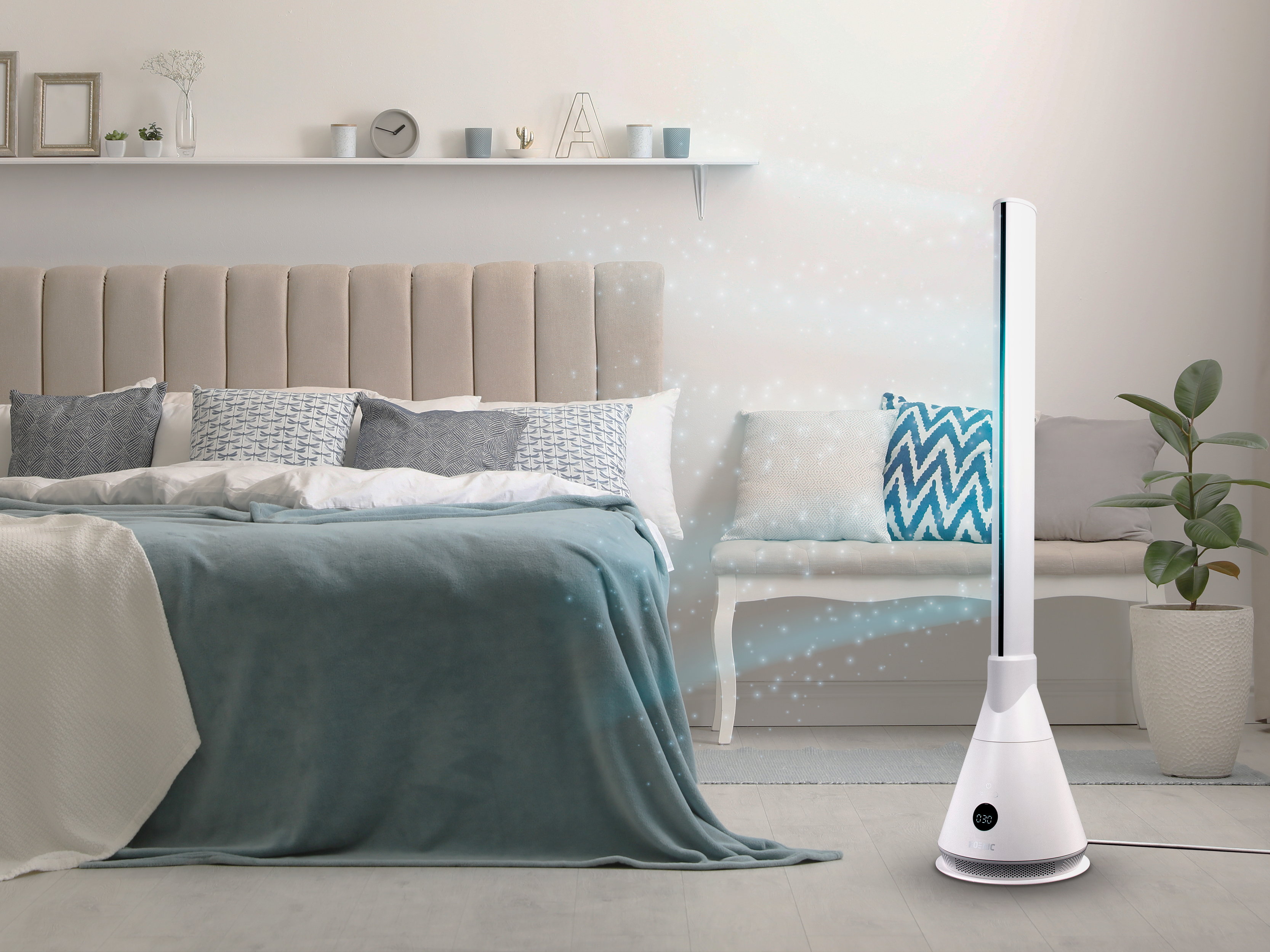 Ein weißer Turmventilator steht neben einem Bett mit blauen Decken. Draußen leuchten Sterne.