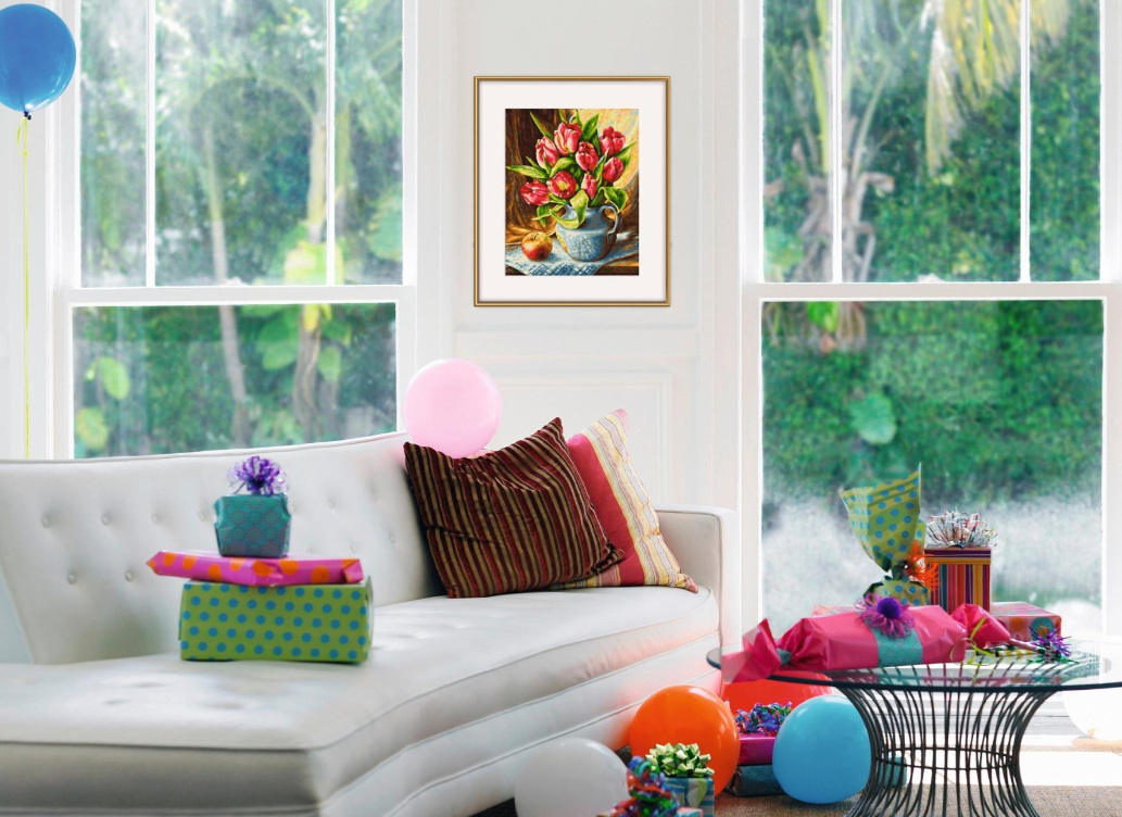 Ein Sofa mit Geschenken und Ballons vor zwei Fenstern mit Blick auf grüne Bäume.