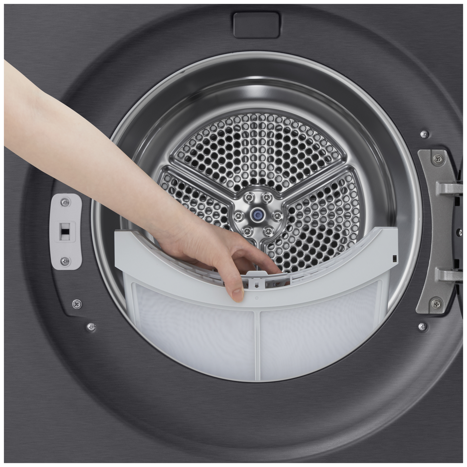 A hand pulls a white lint filter from a dark dryer drum.