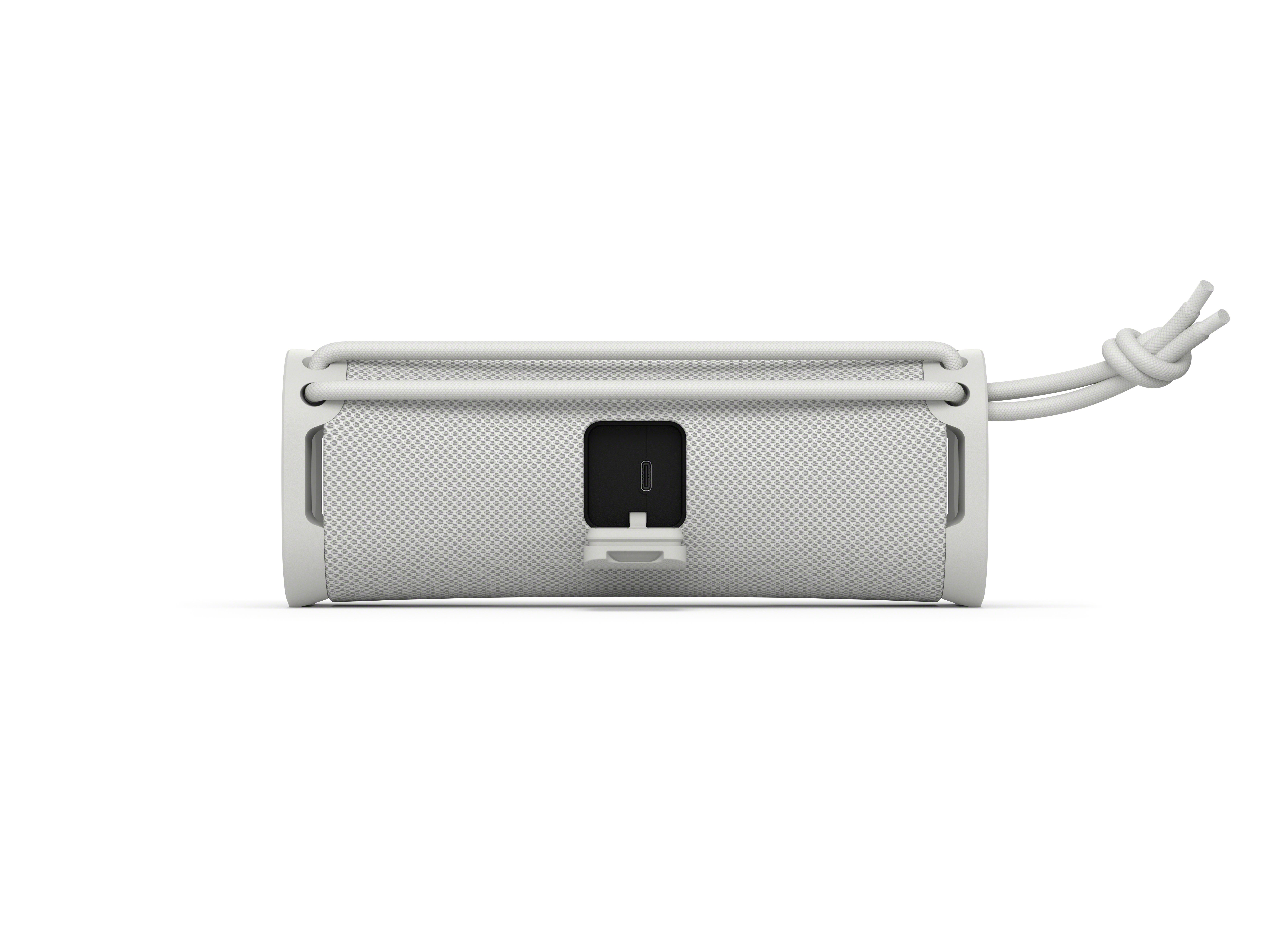 Un altoparlante portatile bianco con porta USB-C e cavo.