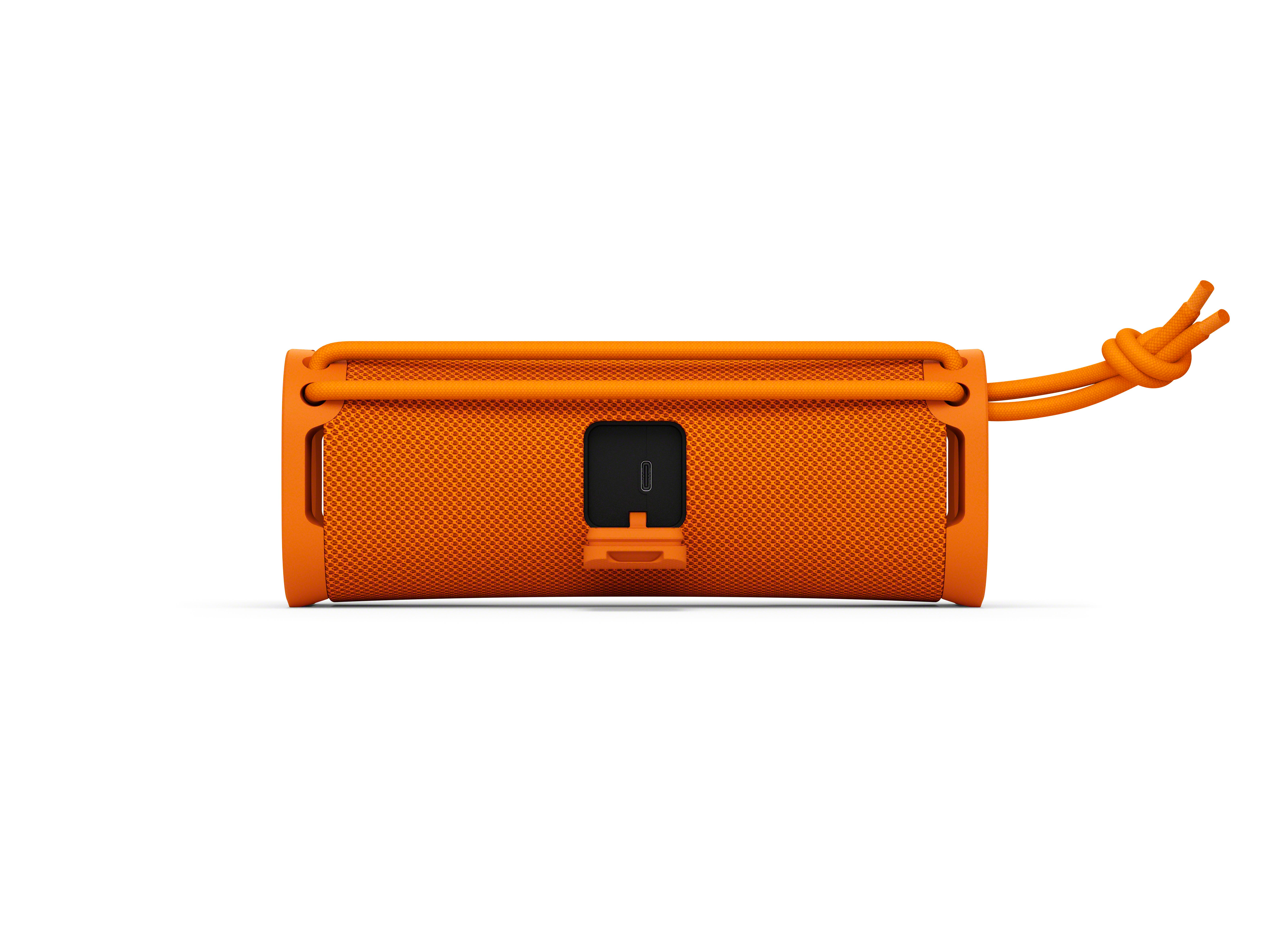Altoparlante Bluetooth arancione con copertura in tessuto e porta di ricarica.
