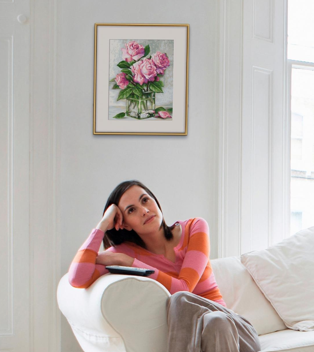 Eine Frau sitzt auf einem Sofa vor einem Bild von Rosen in einer Vase.