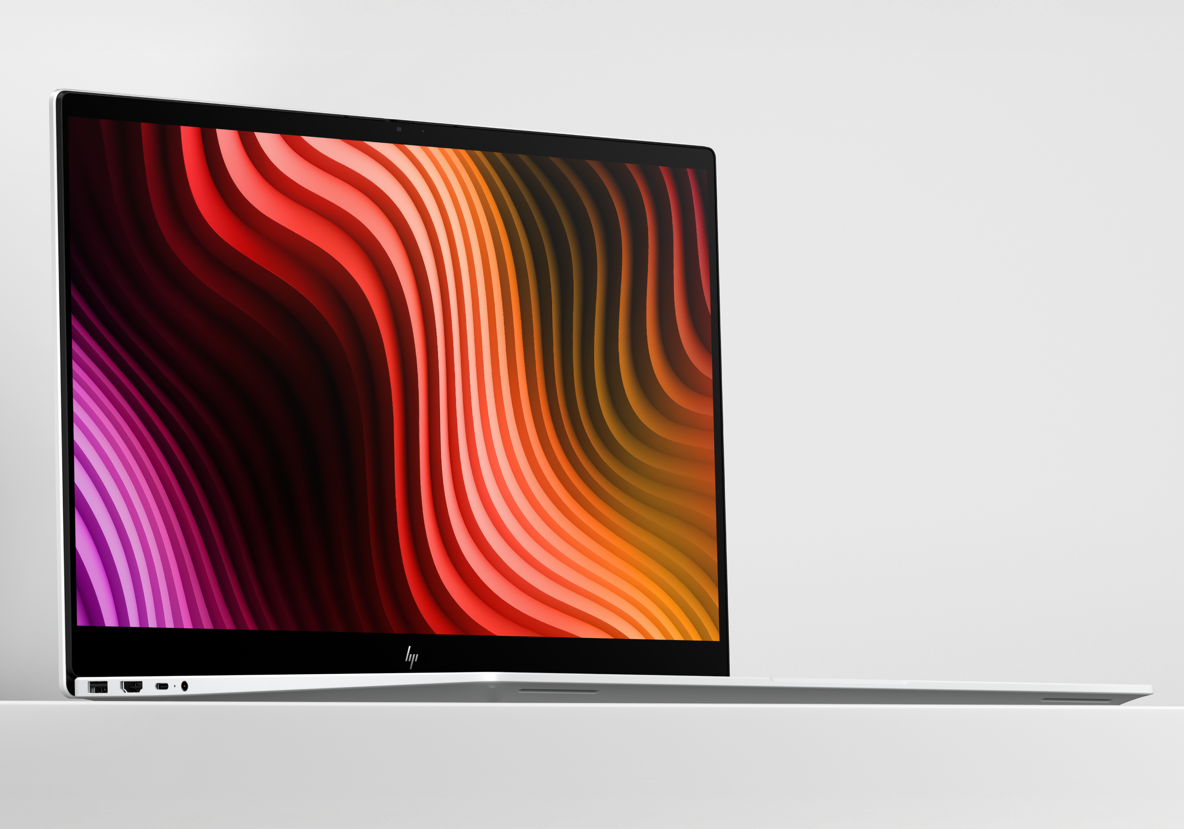 Otwarty laptop wyświetlający na ekranie żywe, faliste tło.