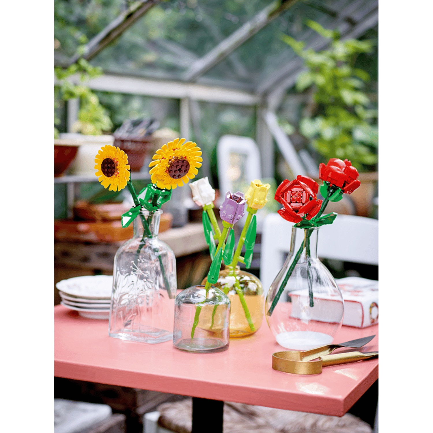 Fleurs Lego : tournesols jaunes, roses rouges, tulipes violettes et jaunes dans des vases.