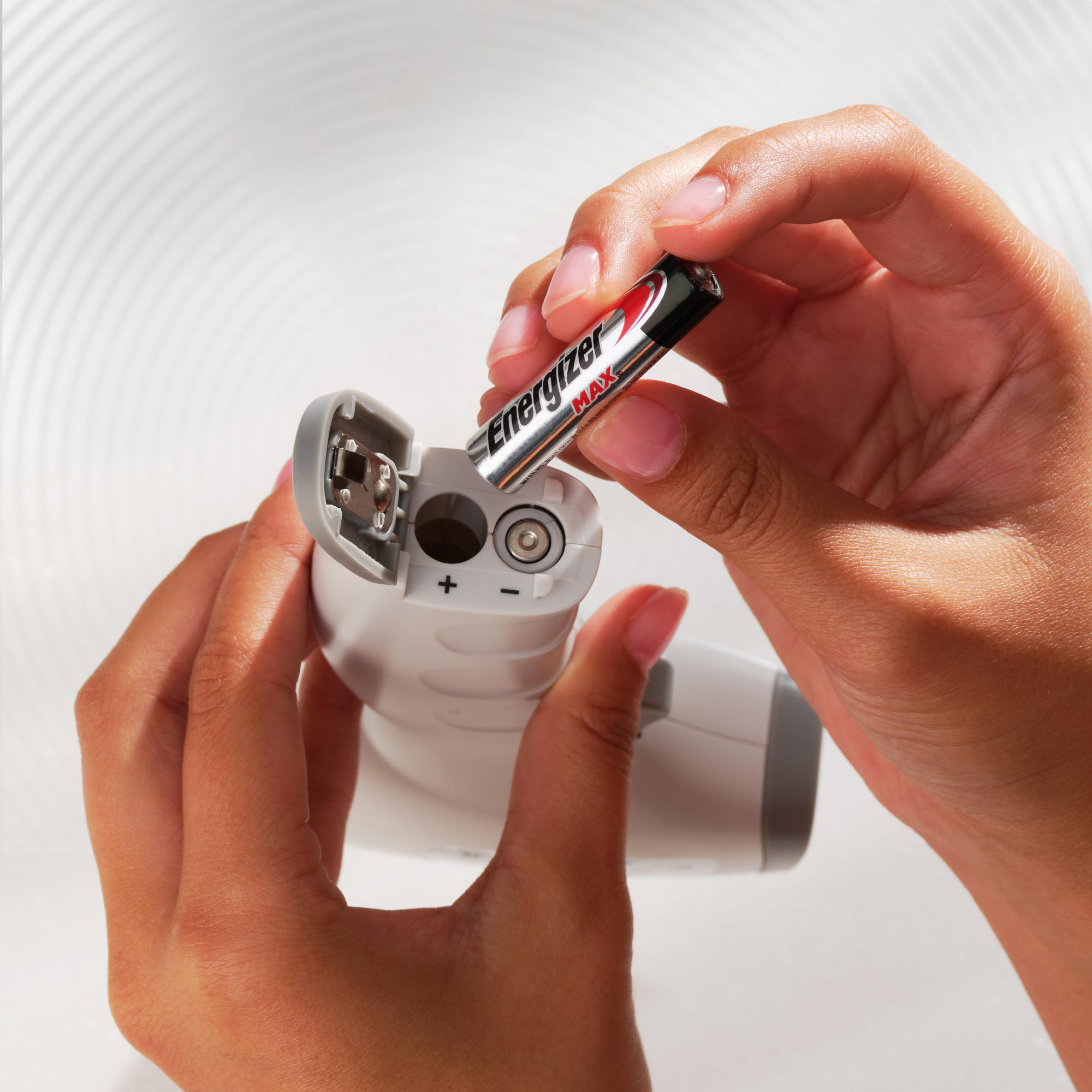 Person setzt eine Energizer Max Batterie in ein weißes Gerät ein.