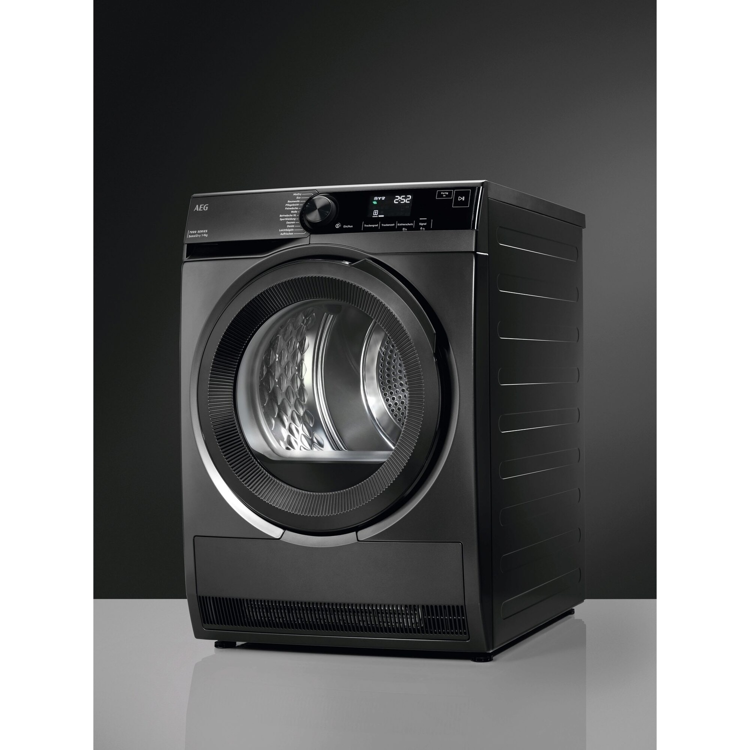 Un sèche-linge AEG noir avec écran numérique est posé sur une surface grise.