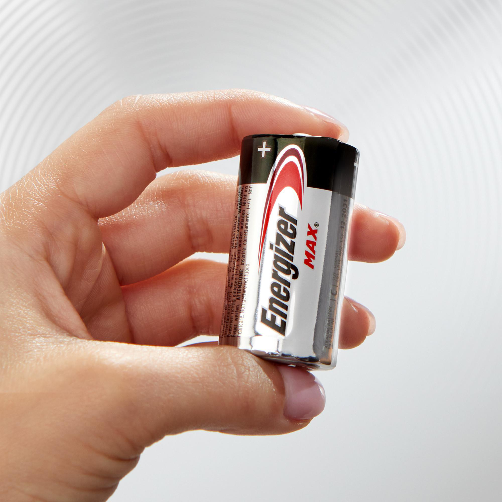 Eine Hand hält eine Energizer Max AA-Batterie vor einem hellen Hintergrund.