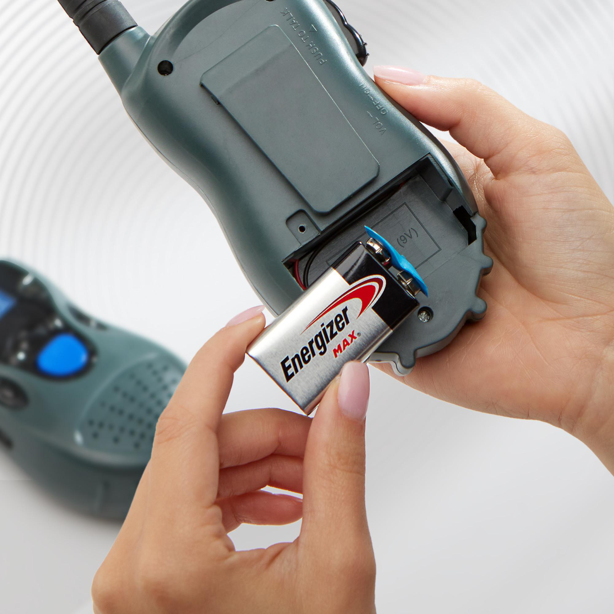 Hände setzen 9V Energizer Max Batterie in graues Walkie-Talkie ein.