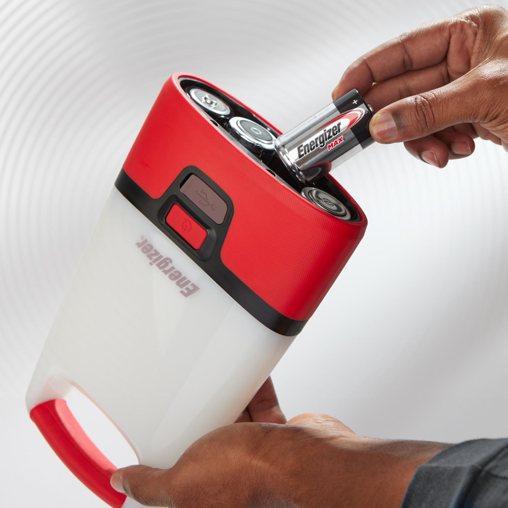 Eine Hand setzt eine Energizer Max Batterie in eine rote und weiße Laterne ein.