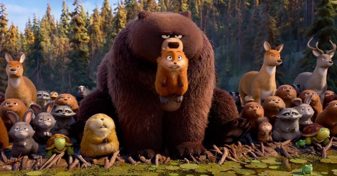 Ein Braunbär steht vor einer Gruppe von Waldtieren im Wald.