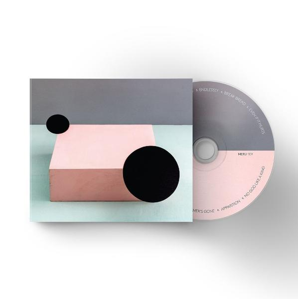 Ein rosa Block mit schwarzen Kreisen sitzt auf einer mintgrünen Oberfläche, neben einer CD.