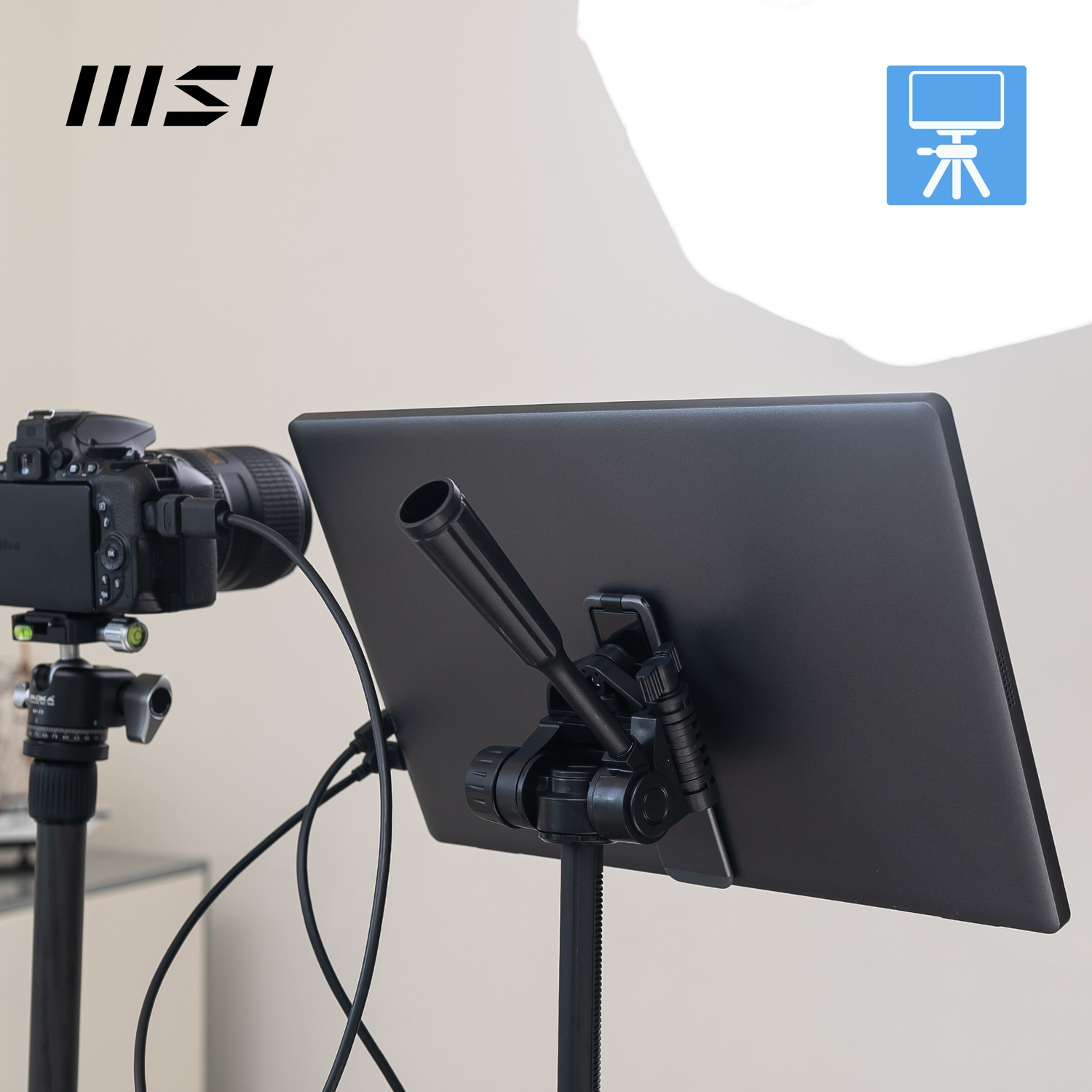 Un laptop su un treppiede con una fotocamera accanto, logo MSI in alto a sinistra.