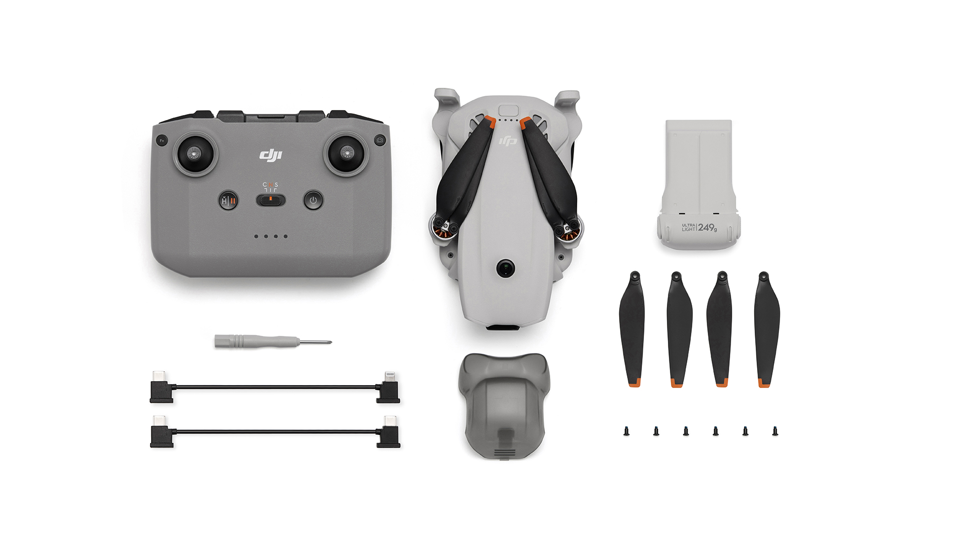 Gri DJI kumanda, drone, yedek pervaneler, pil ve aksesuarlar beyaz zeminde.