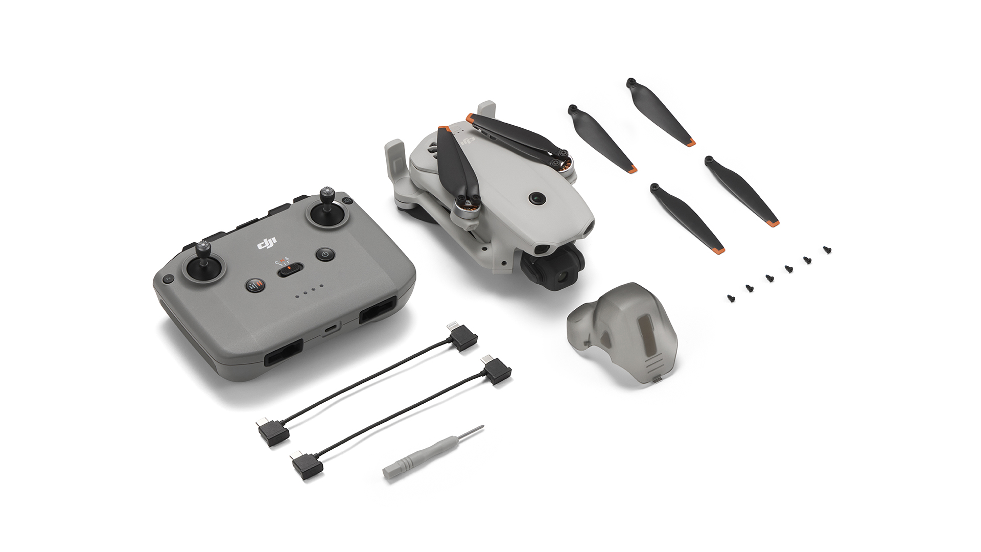 Gri DJI Mini 3 Pro drone kiti, kontrolcü, yedek pervaneler ve kablolarla.