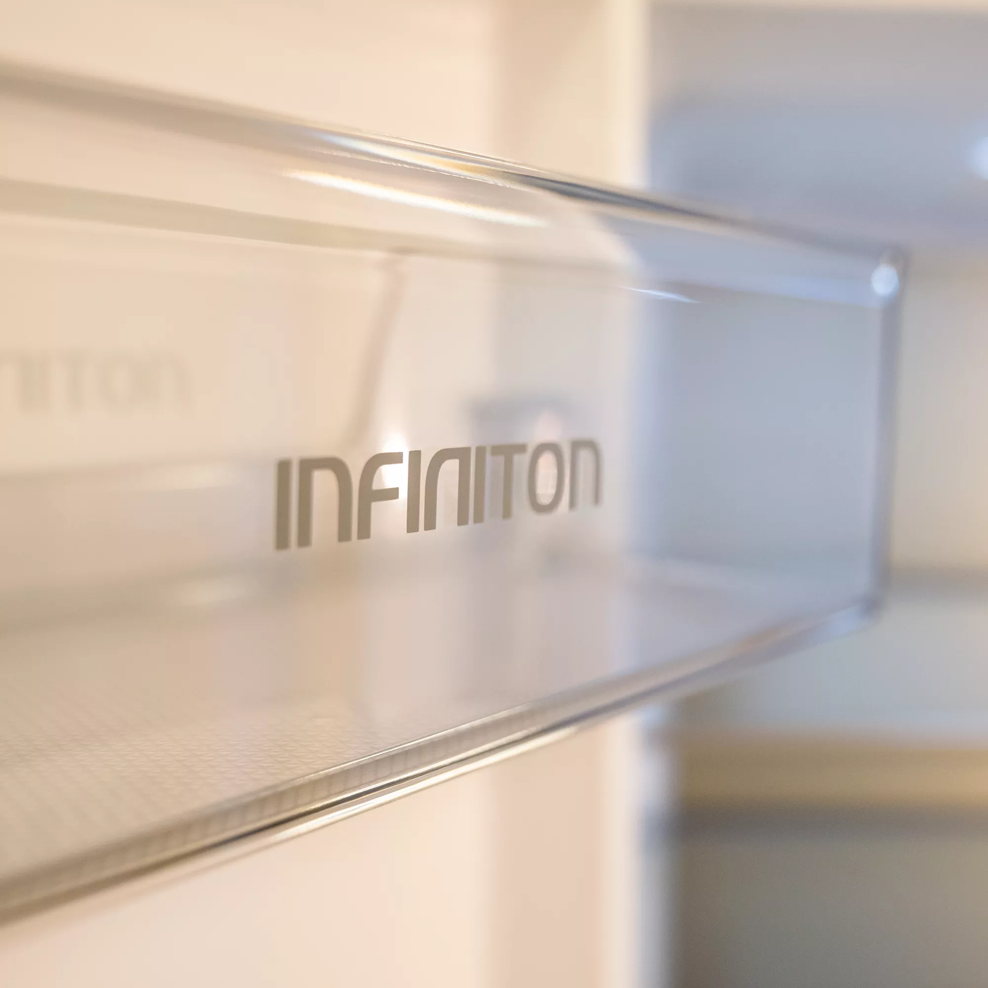 Interior de un frigorífico con el logo INFINITON en una balda de cristal.