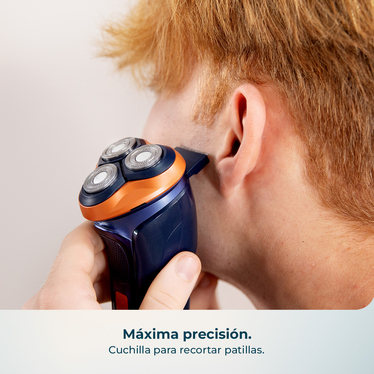Un hombre se recorta las patillas con una afeitadora eléctrica azul y naranja.