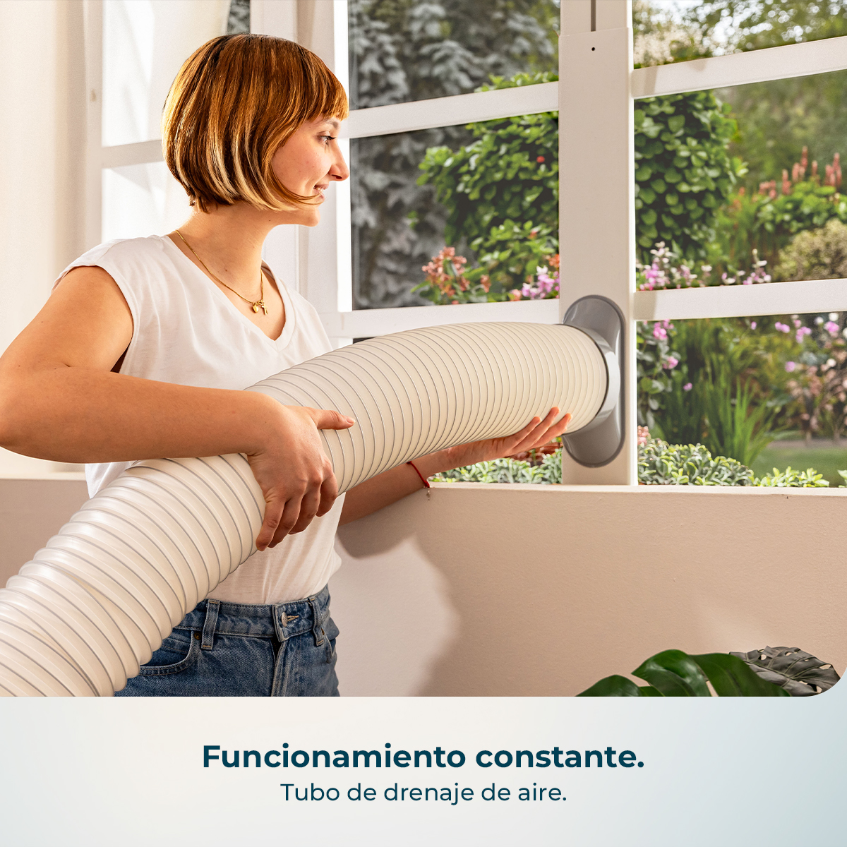Mujer instalando un conducto de aire flexible a través de una ventana a un jardín.
