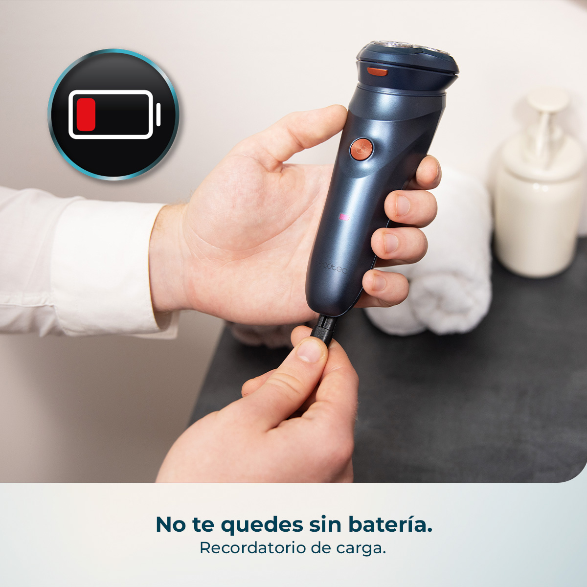 Hombre conecta cable de carga a afeitadora oscura. Icono de batería a la izq.
