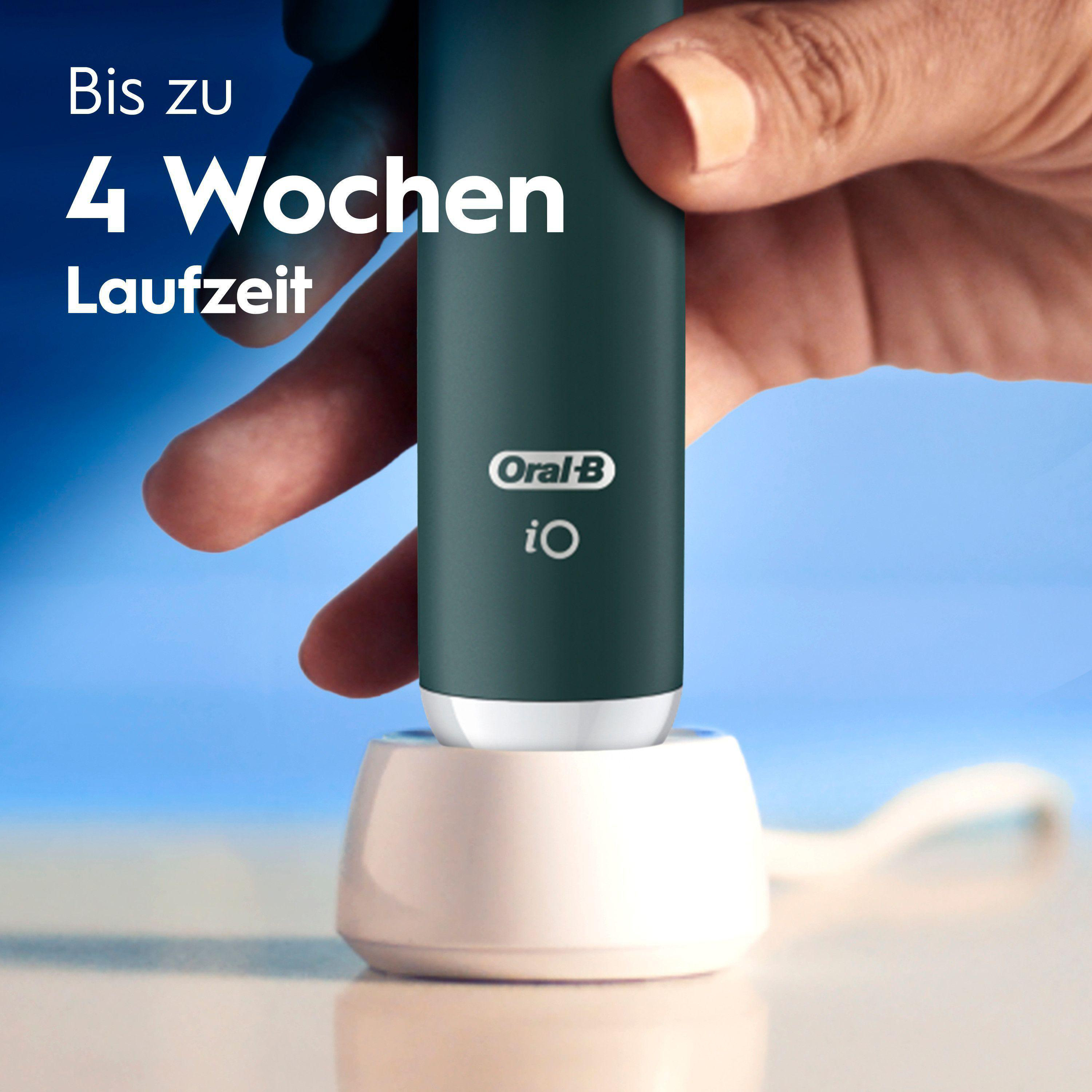 Eine Hand hält eine grüne Zahnbürste über einer Ladestation.