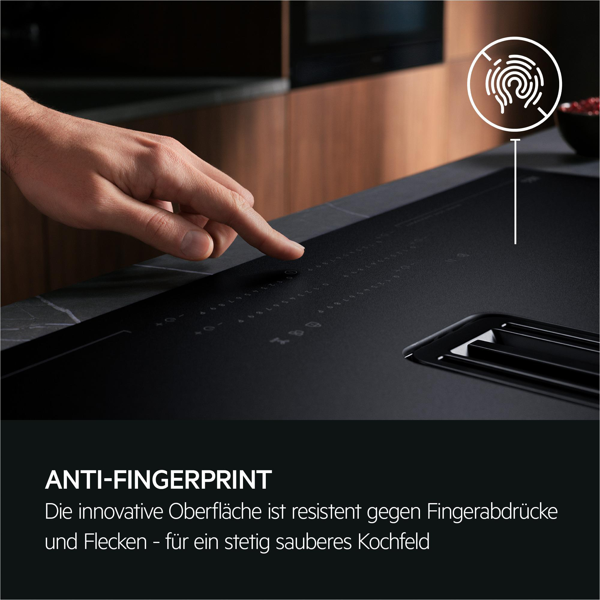 Eine Hand berührt ein schwarzes Kochfeld mit Fingerabdruck-Symbol. Anti-Fingerprint.