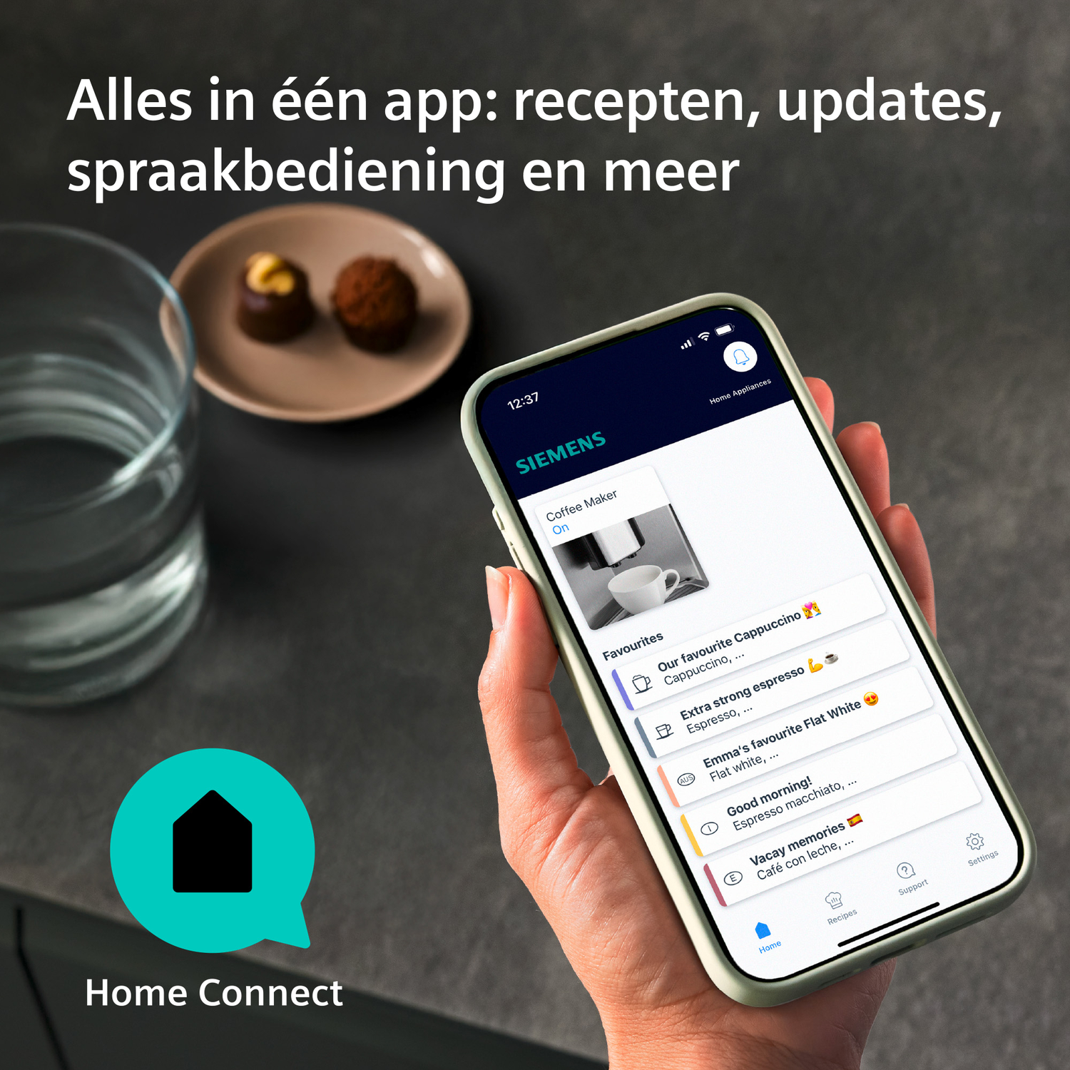 Een hand houdt een smartphone met de Home Connect app vast. Links staan een glas water en een schaaltje met chocolaatjes.