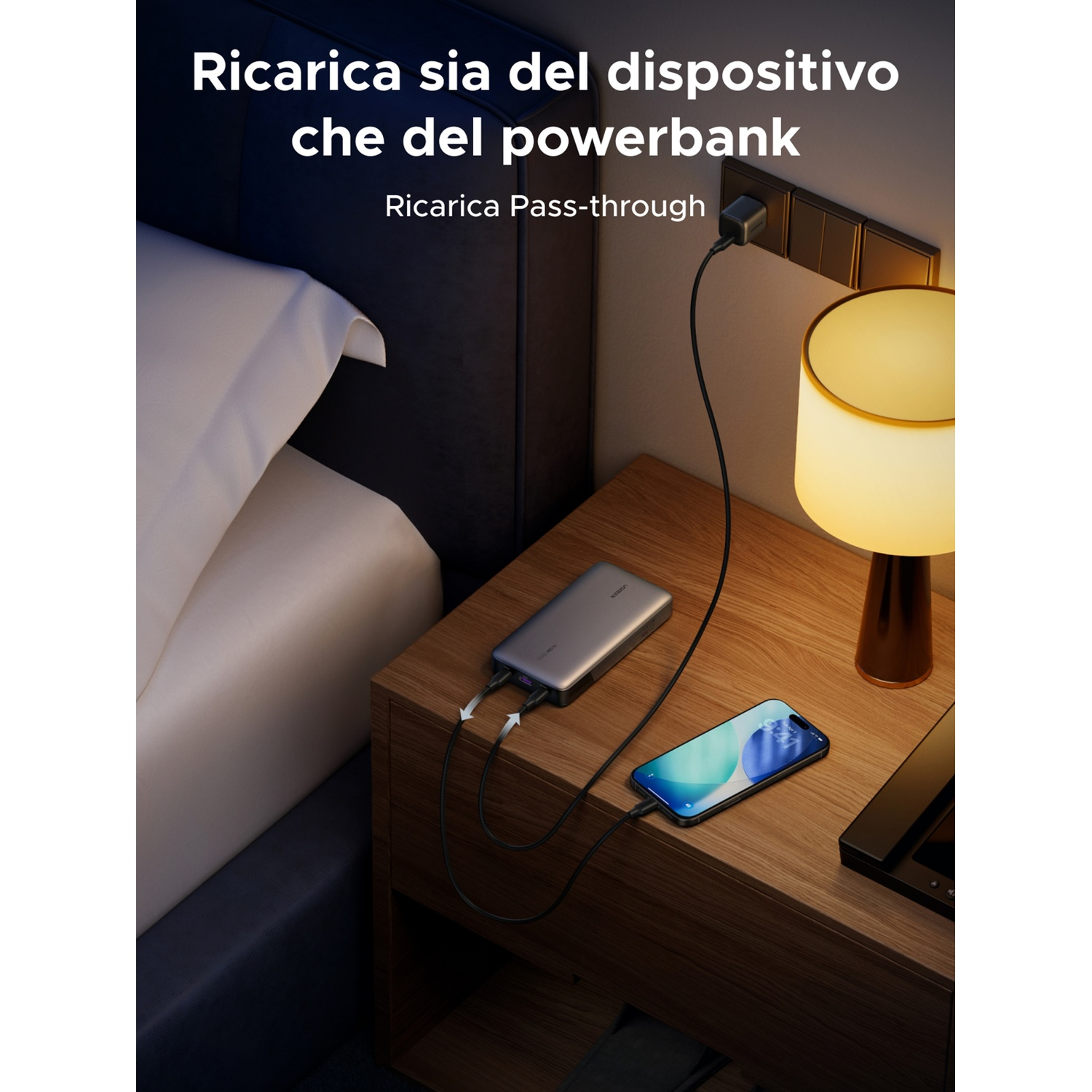 Un powerbank grigio carica uno smartphone su un comodino.