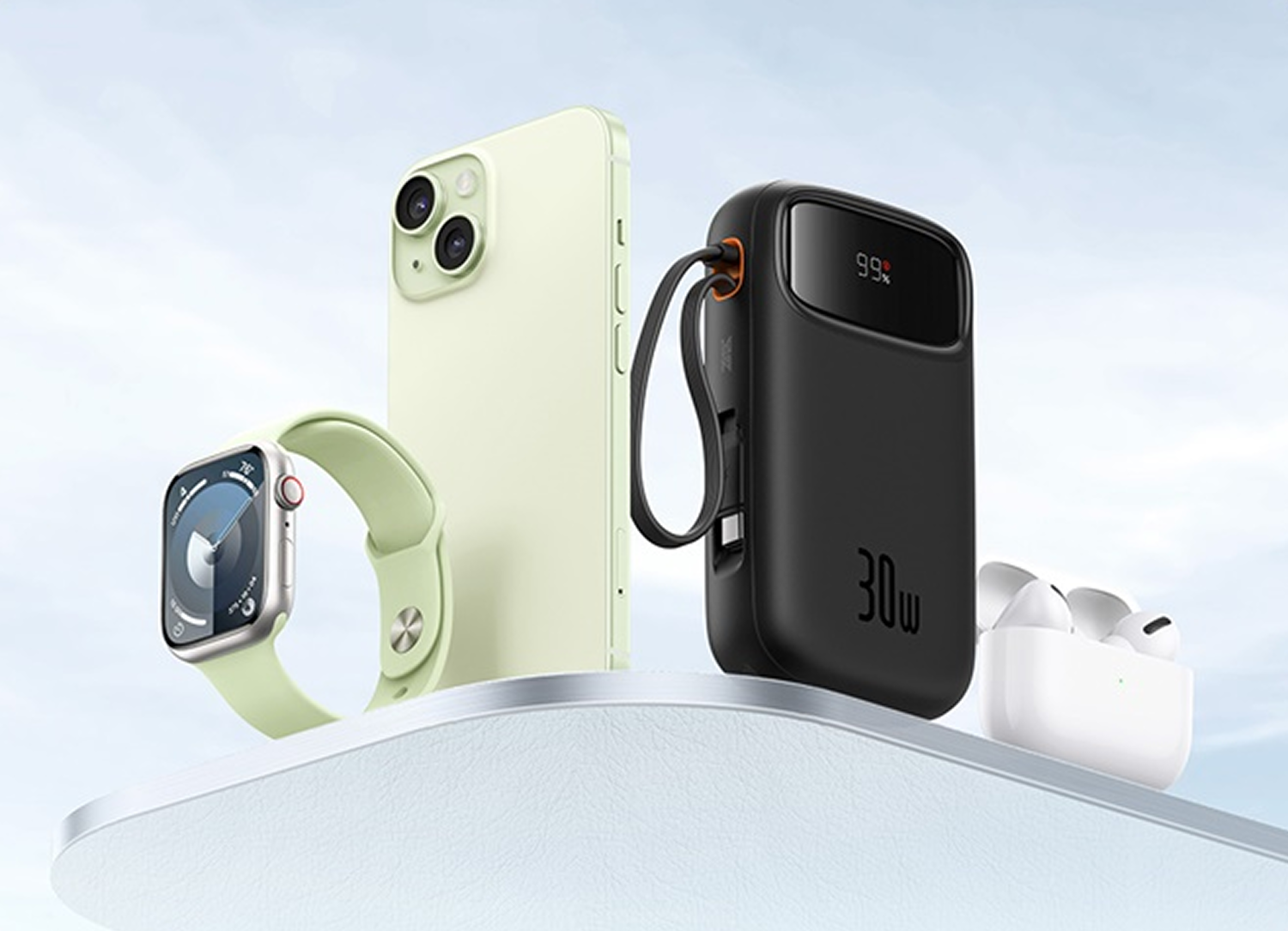 Un iPhone verde claro, un banco de energía negro y auriculares blancos sobre un pedestal.