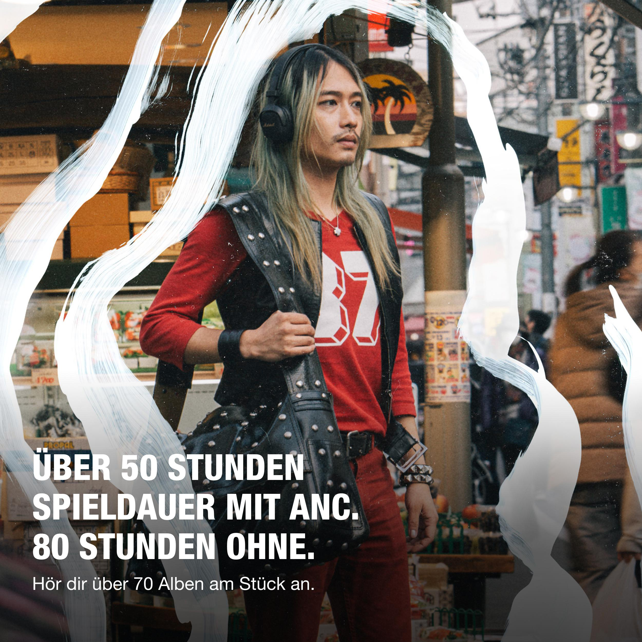 Eine Person mit langen blonden Haaren und schwarzen Kopfhörern trägt ein rotes Hemd und eine schwarze Weste, hält eine Nieten-Tasche, auf einer belebten Straße.