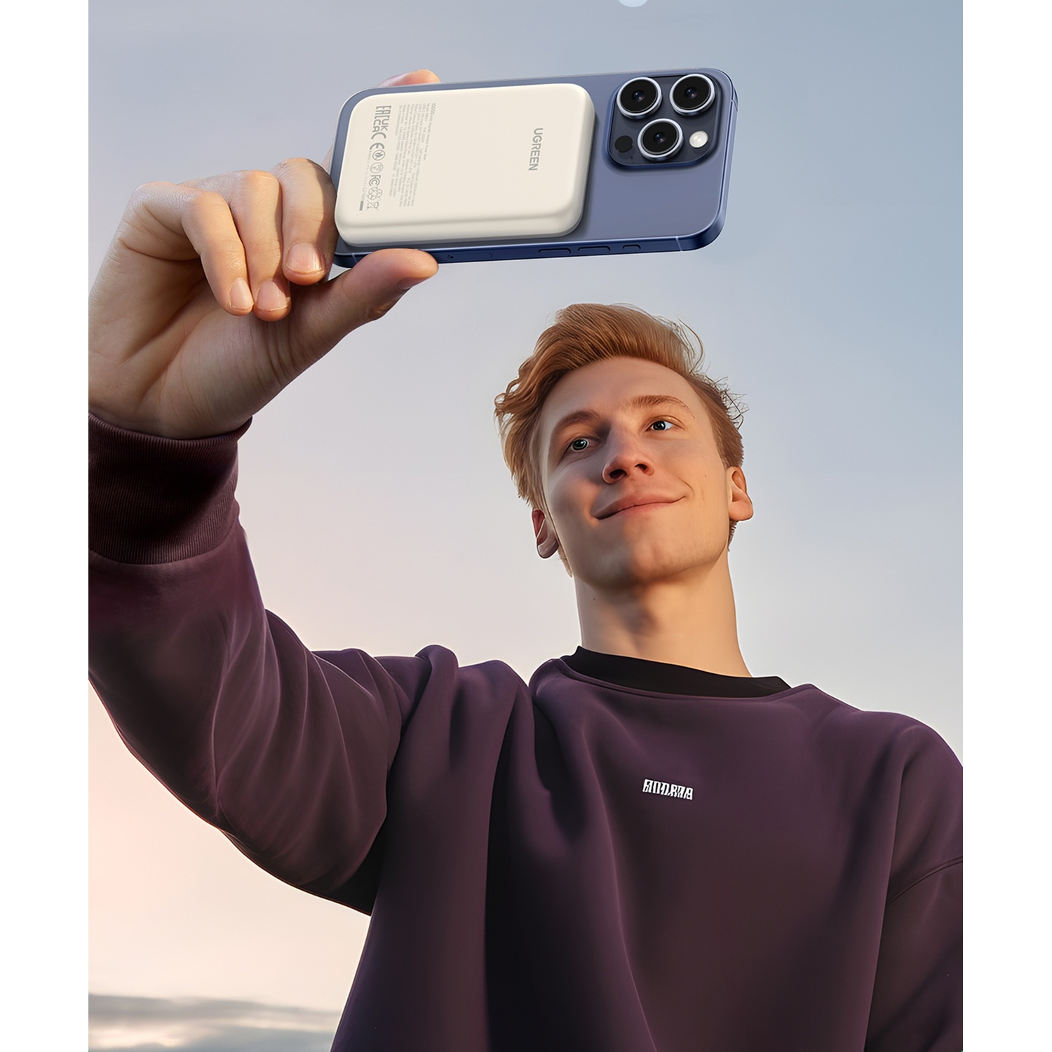 Uomo tiene telefono con power bank contro cielo azzurro