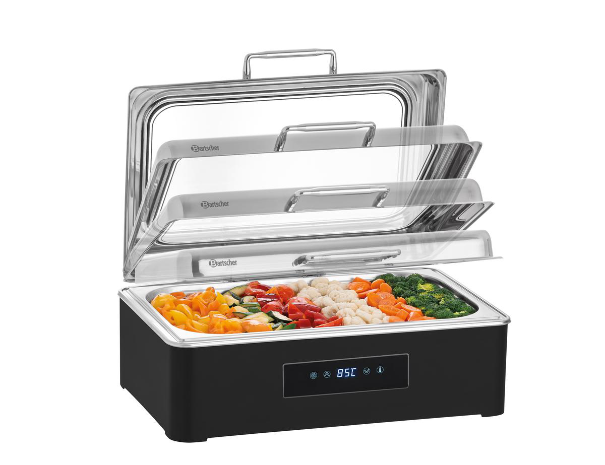 Ein schwarzer Chafing Dish mit drei Ebenen und transparentem Deckel. Er enthält bunte gekochte Gemüsesorten.