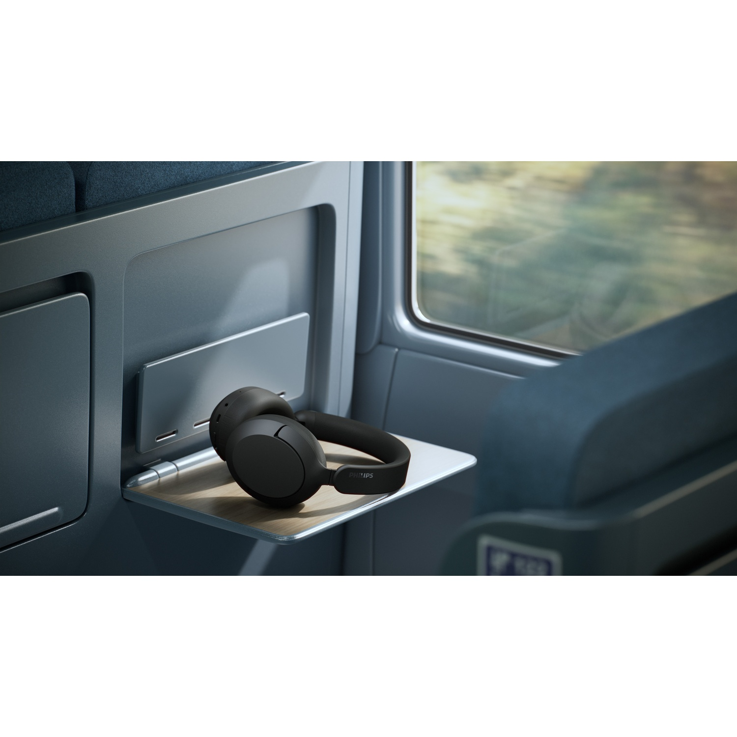 Cuffie nere su un tavolino in un treno, vicino al finestrino.