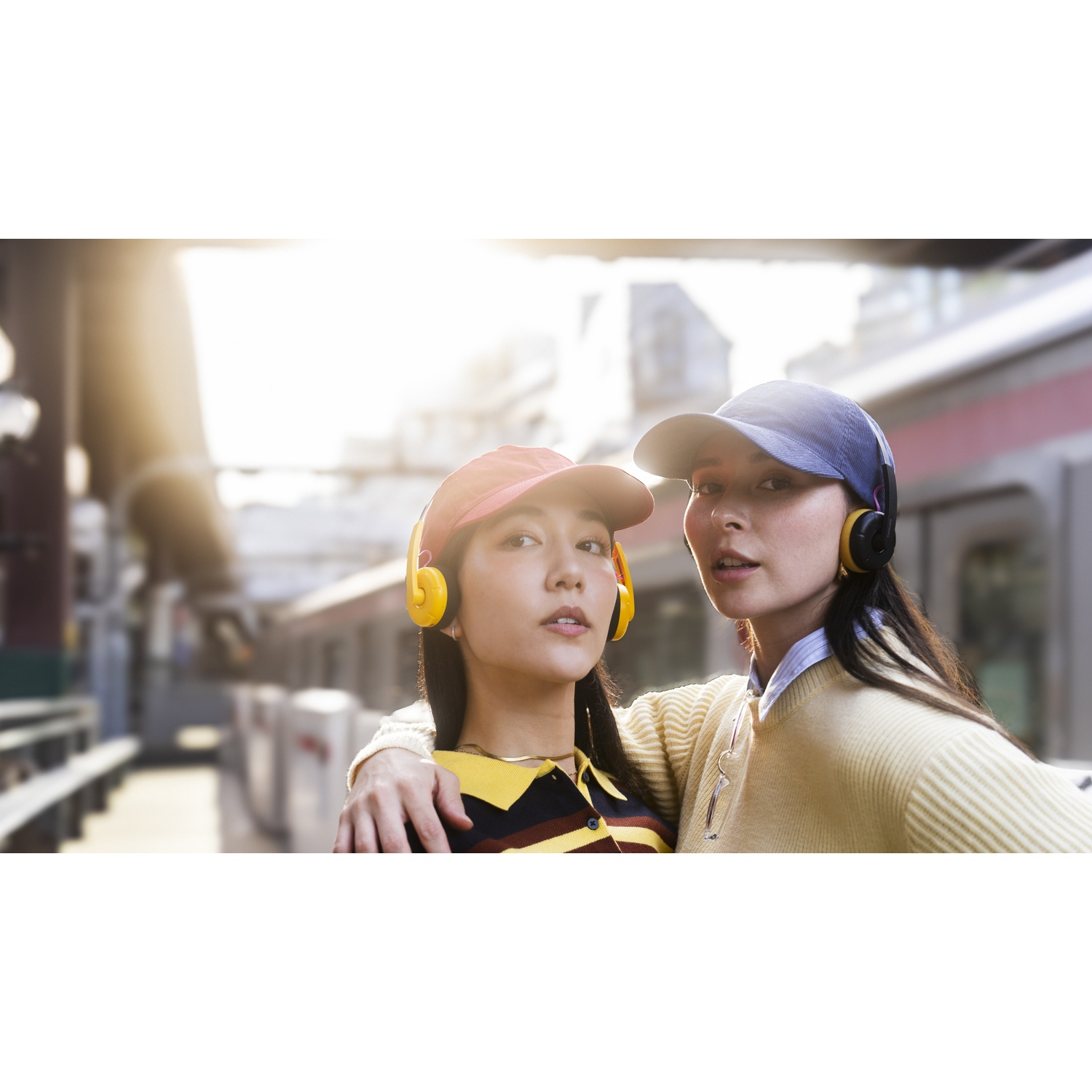 Due donne con cuffie e cappelli stanno davanti a un treno.