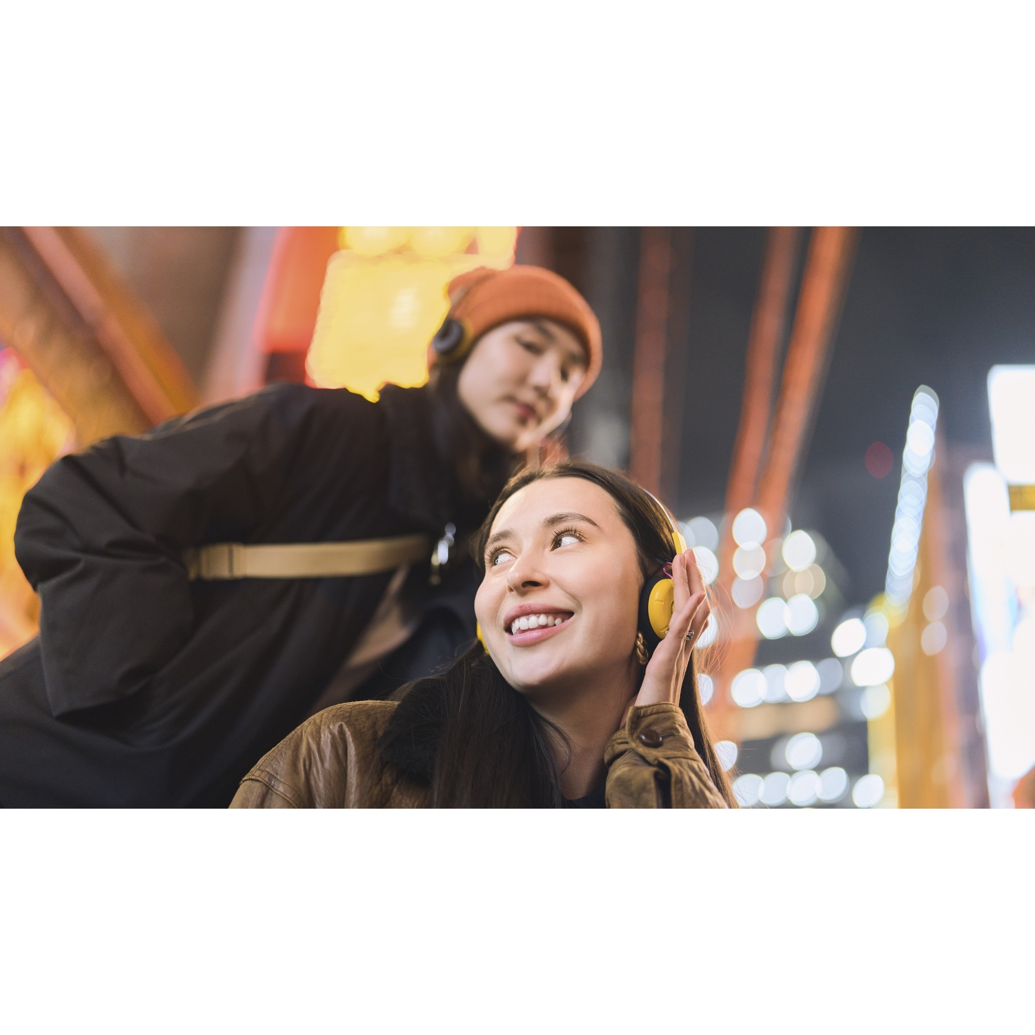 Due donne con cuffie in una città illuminata di notte.