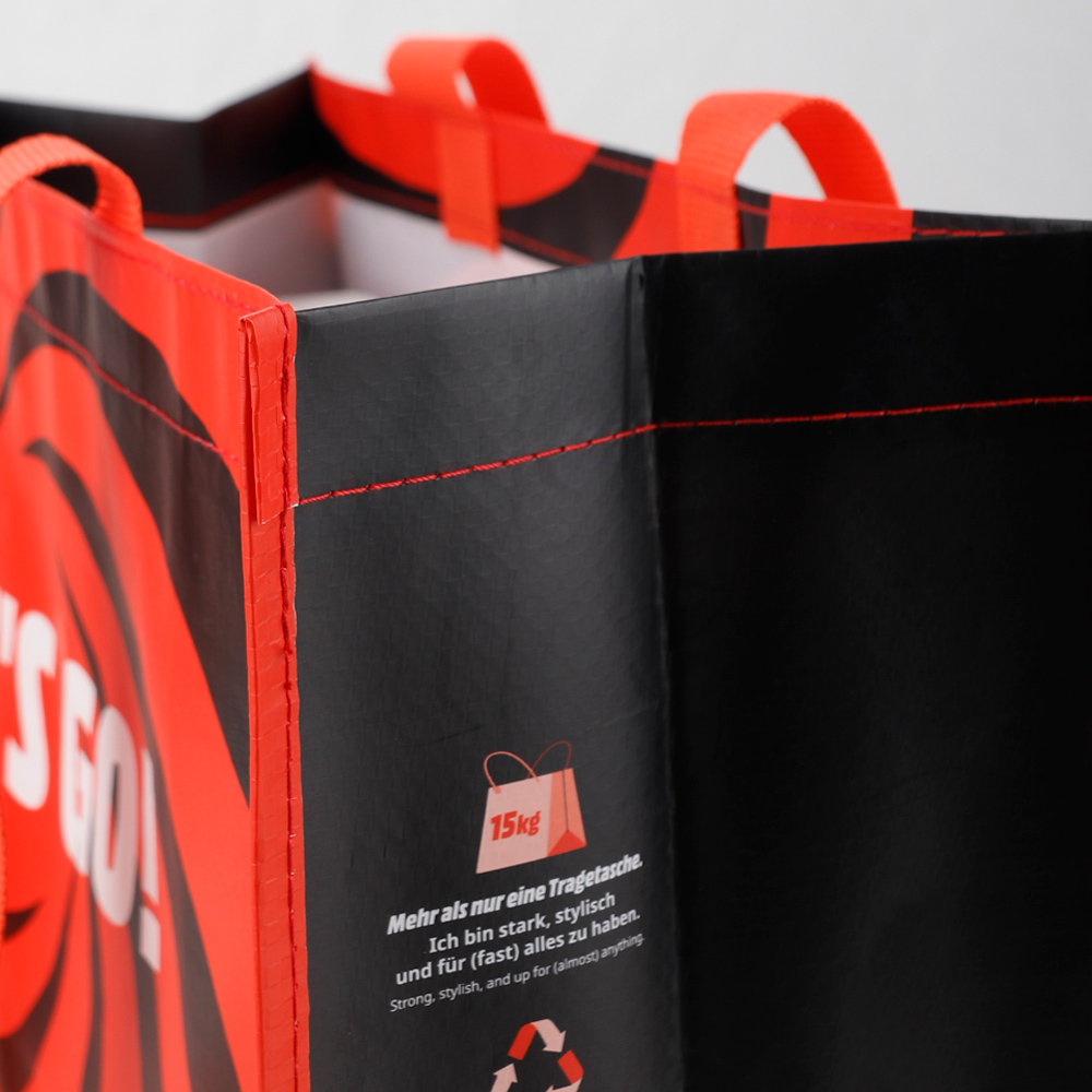 Schwarze und rote Einkaufstasche mit Henkeln und Text.
