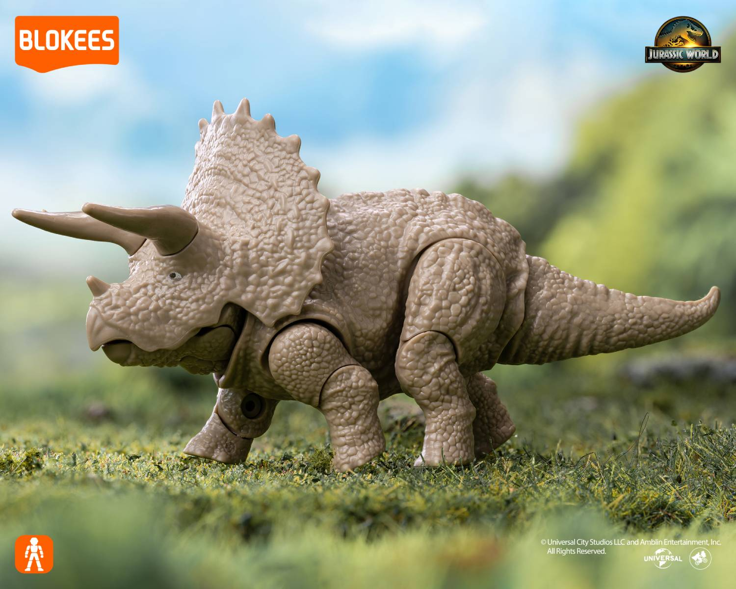 Un dinosaurio de juguete Triceratops beige está sobre hierba verde.