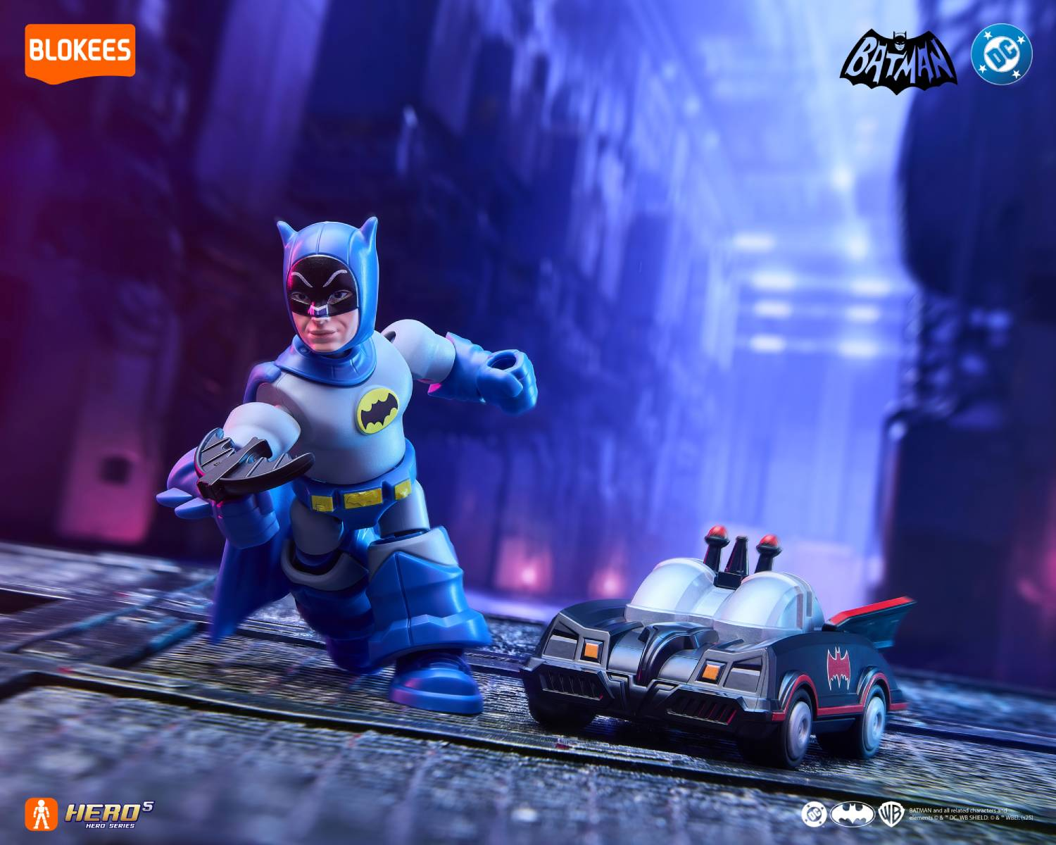 Una figura de juguete de Batman está junto a un Batimóvil de juguete en una calle de la ciudad por la noche.