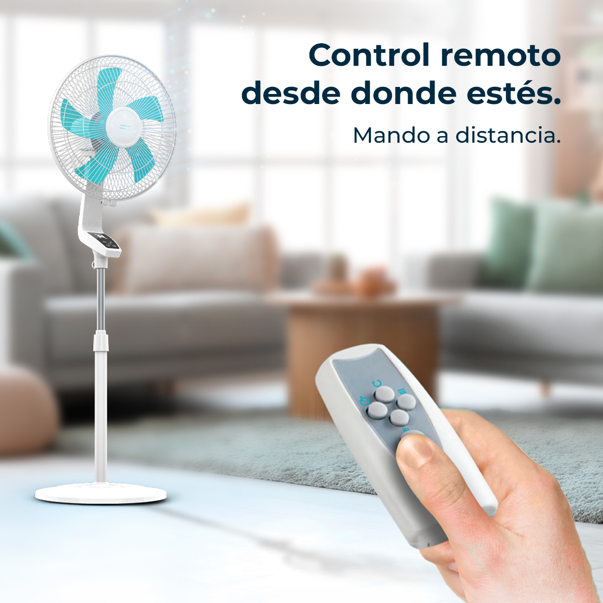 Un ventilador de pie blanco con aspas azules es sostenido por una mano con mando a distancia.
