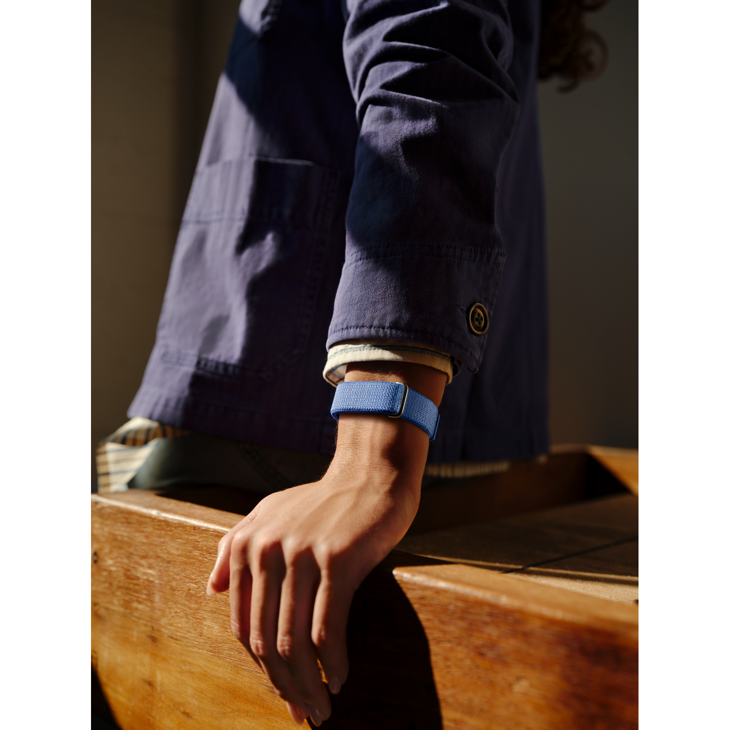 Arm met blauwe band op houten tafel.
