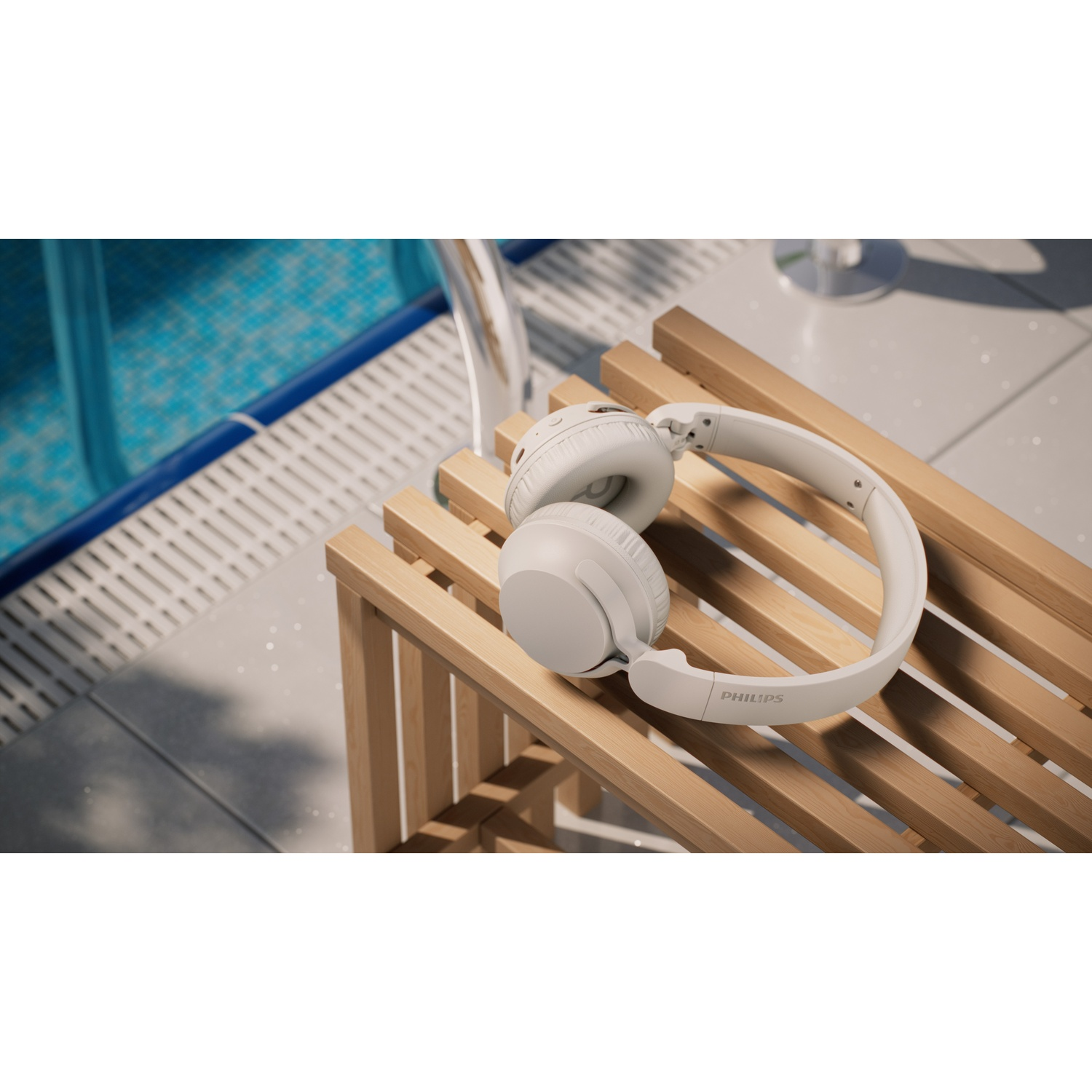 Cuffie bianche riposano su una panchina di legno accanto a una piscina.