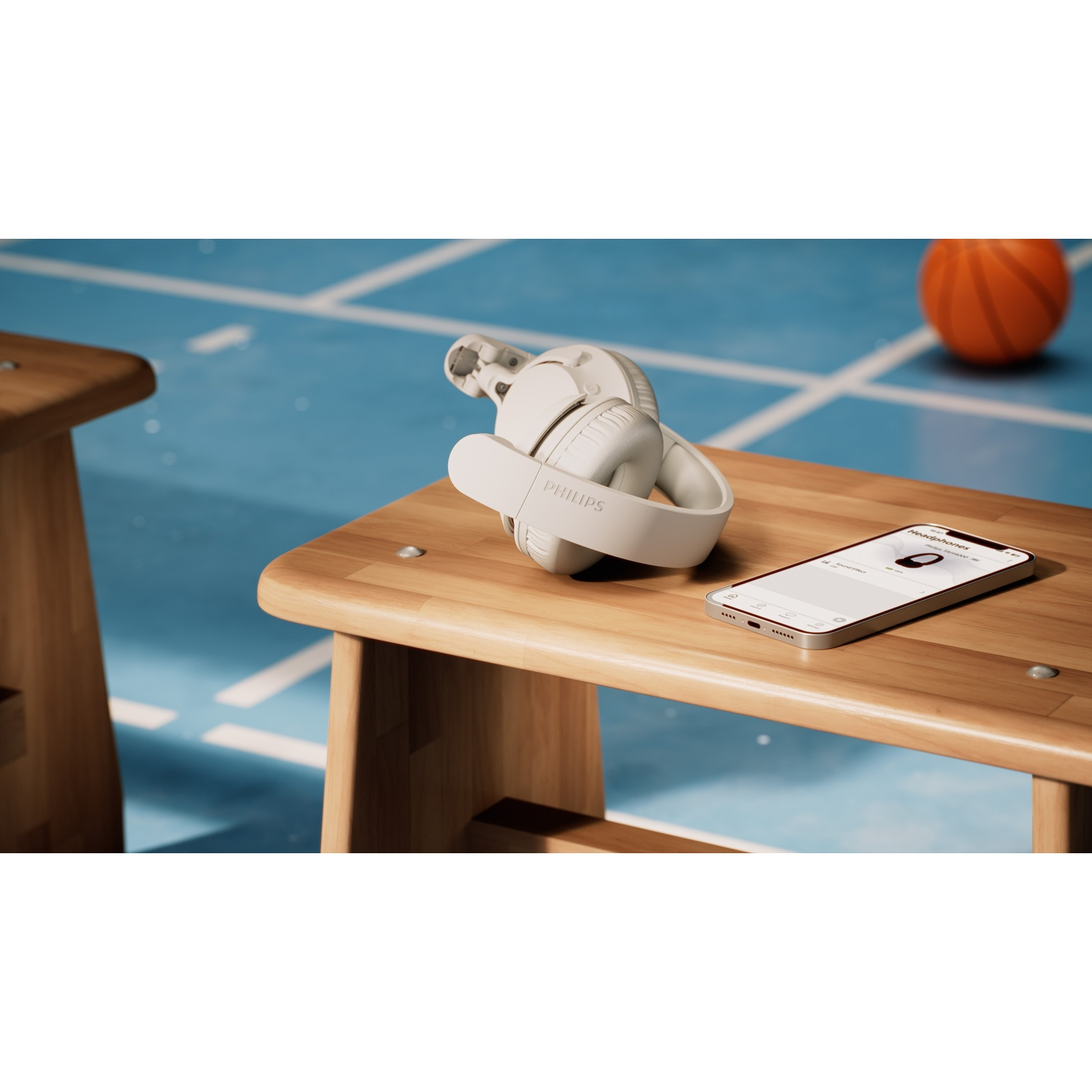 Cuffie bianche e smartphone su una panchina di legno. Un pallone da basket sullo sfondo.