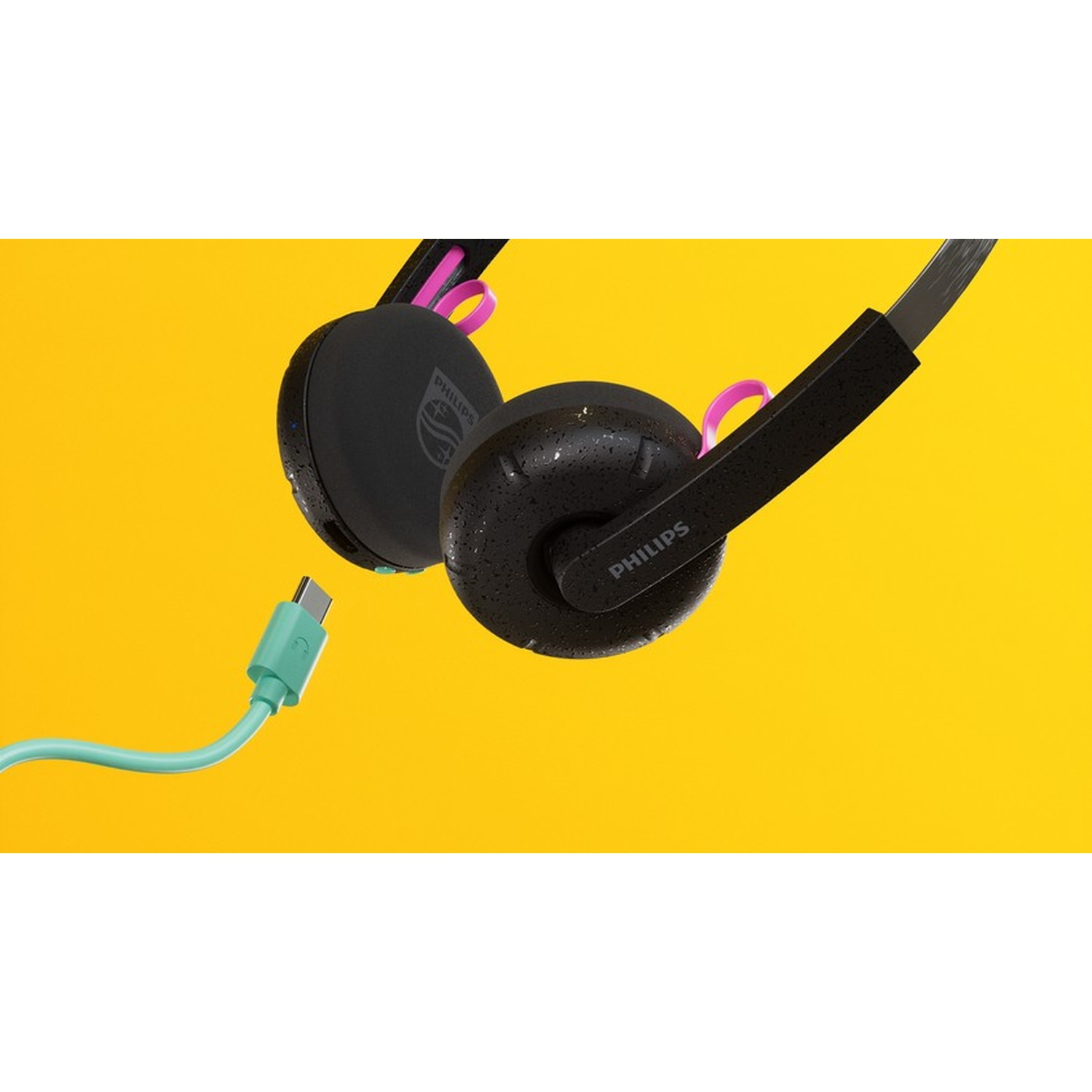 Cuffie nere con accenti rosa e cavo USB-C turchese su sfondo giallo.