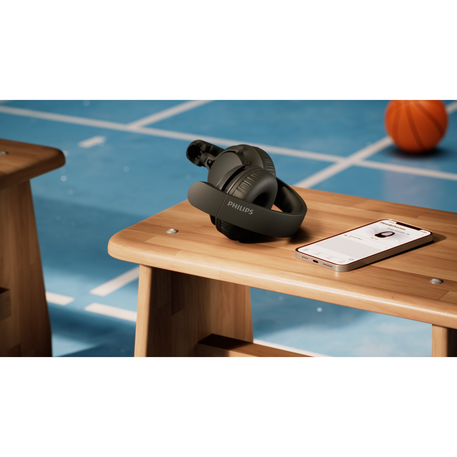 Cuffie nere e smartphone su una panchina di legno. Un pallone da basket sullo sfondo.