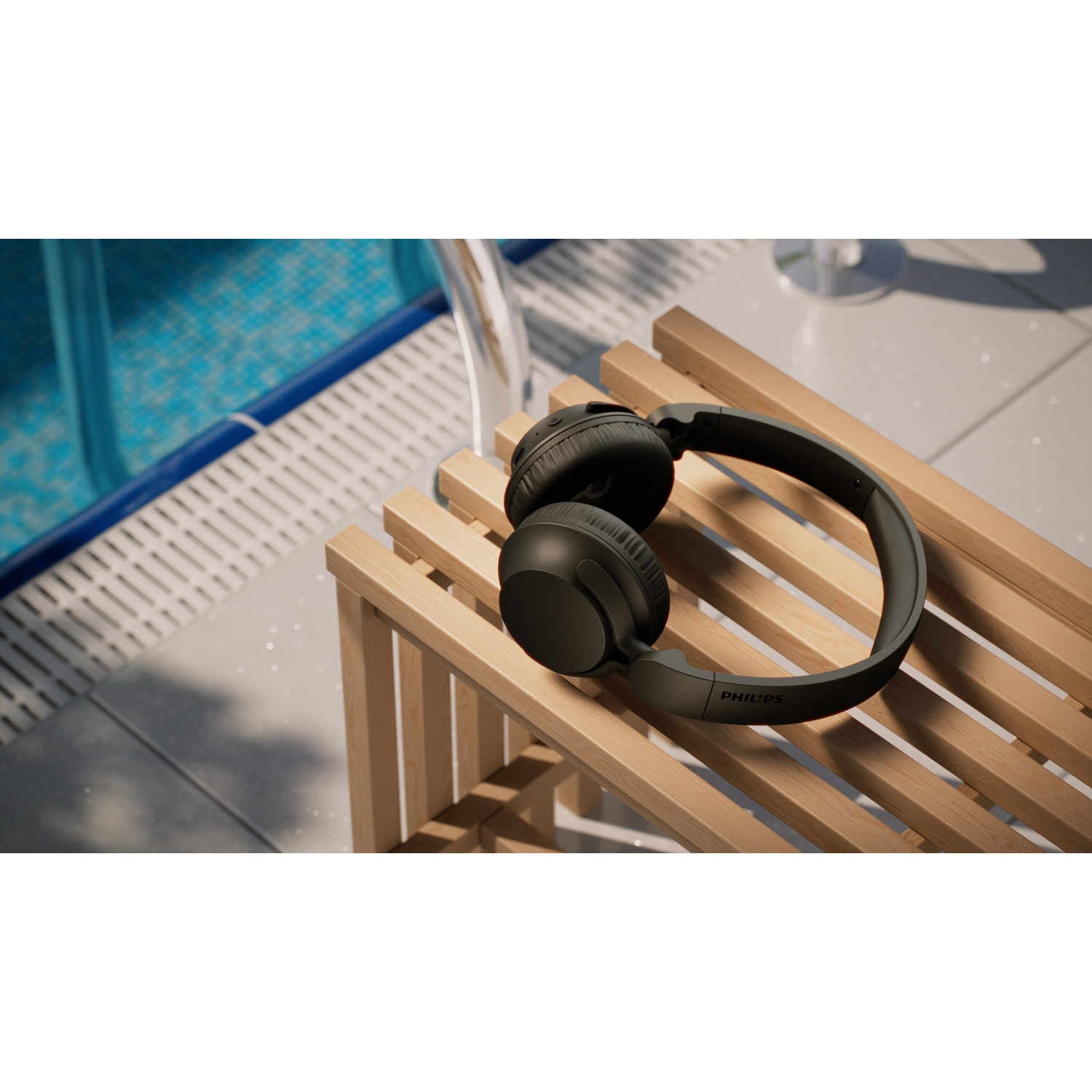 Cuffie Philips nere appoggiate su una panca a doghe di legno accanto a una piscina.