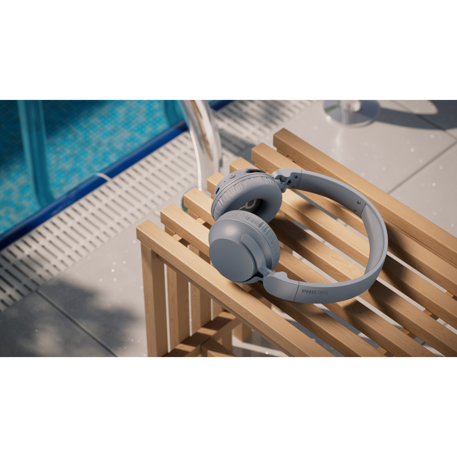 Cuffie grigie su una panca di legno vicino a una piscina.