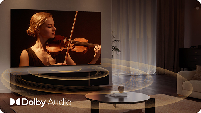 Kobieta gra na skrzypcach na ekranie TV z logo Dolby Audio.