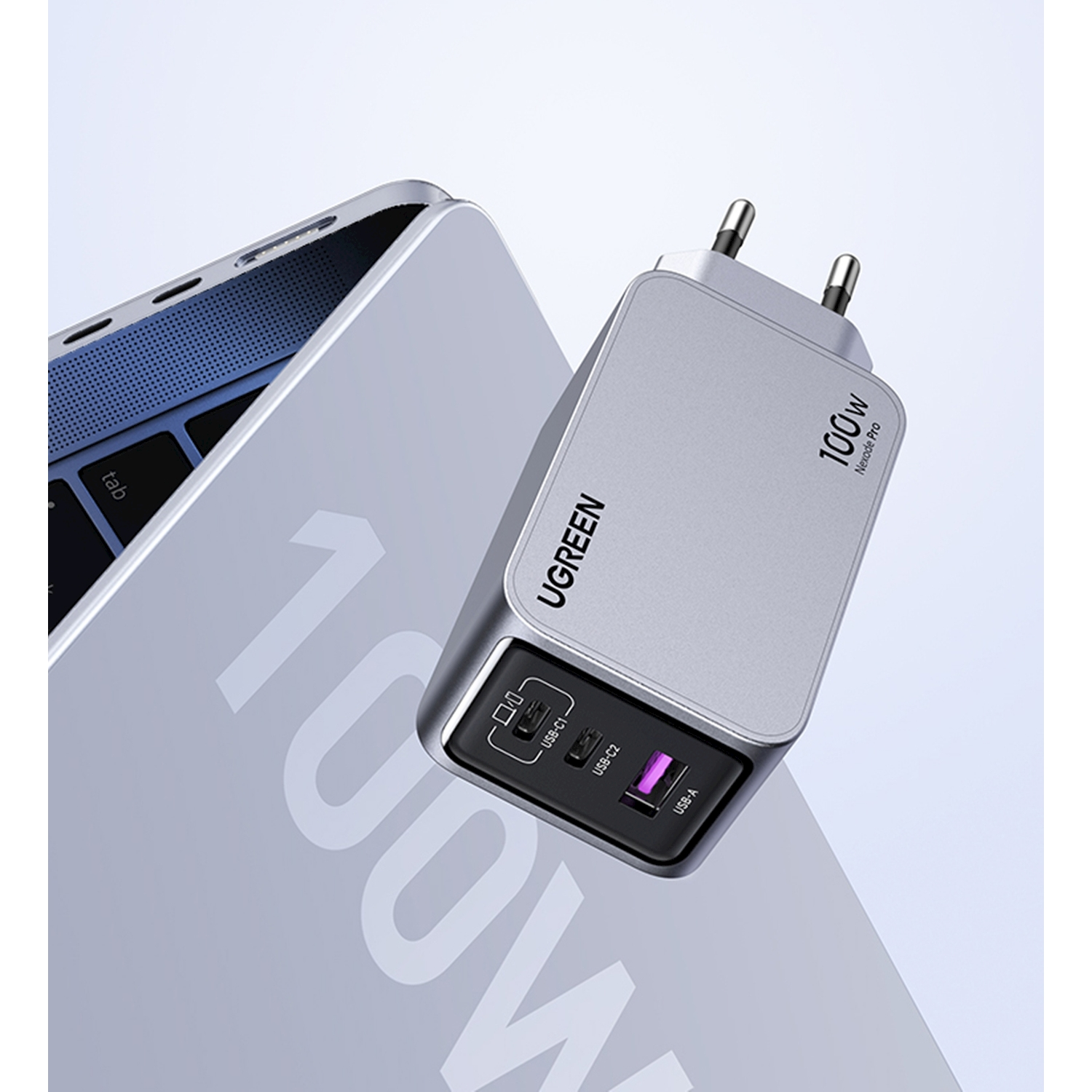 Caricatore UGREEN argento da 100W con porte USB-C1, USB-C2 e USB-A accanto a laptop.