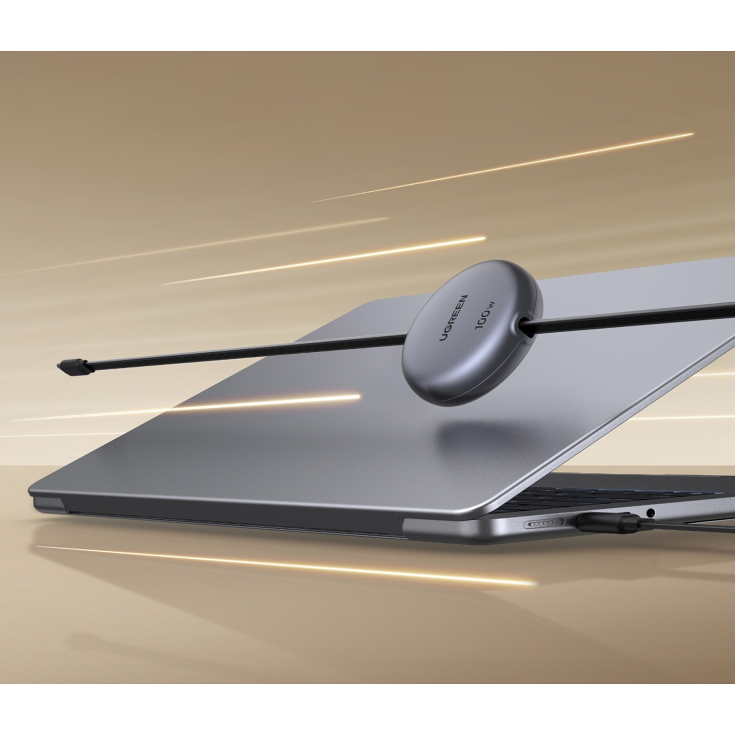 Un laptop grigio con un caricatore argento collegato da un cavo nero.