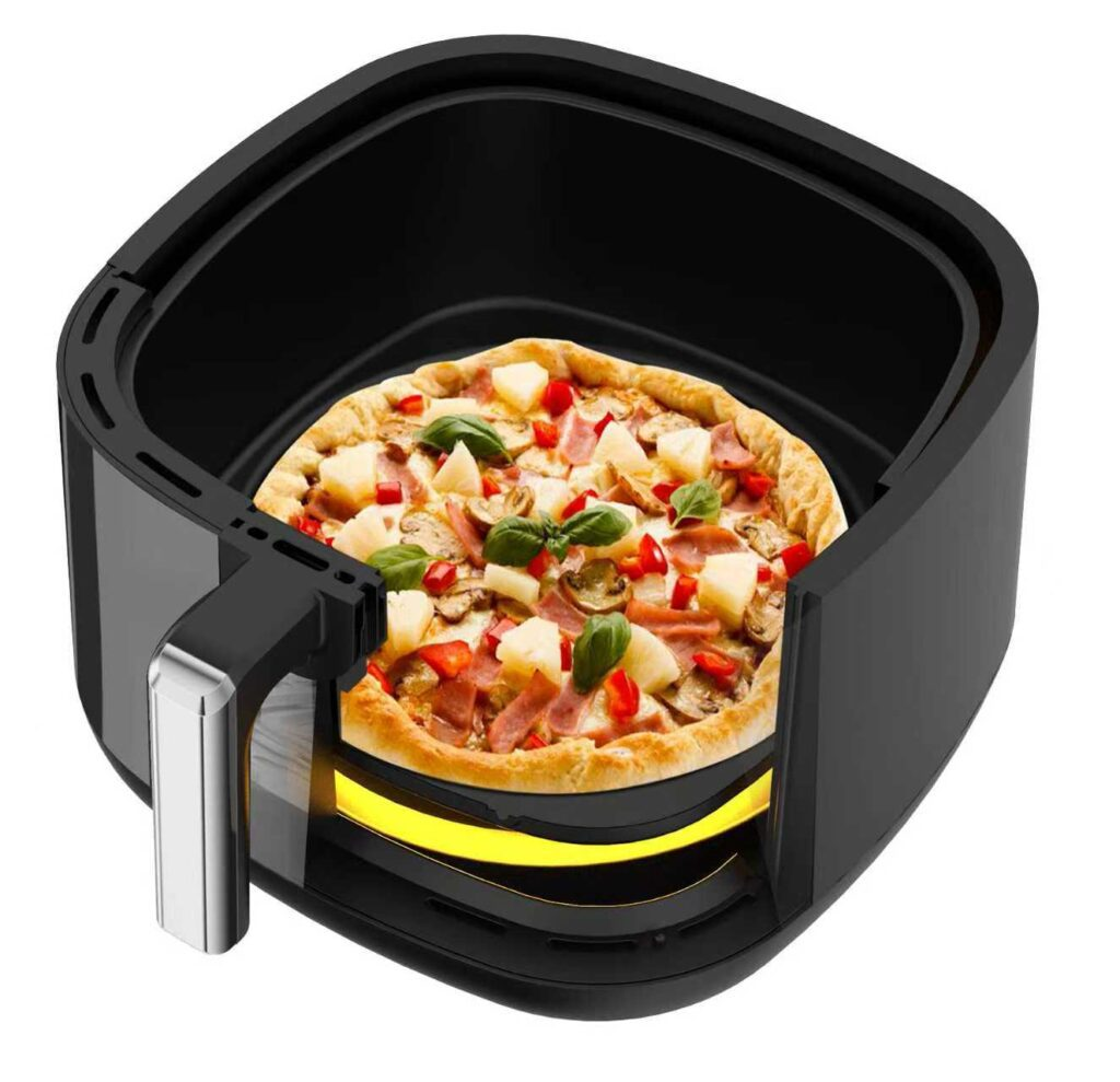 Pizza z ananasem, szynką i papryką w czarnym koszu frytkownicy beztłuszczowej.